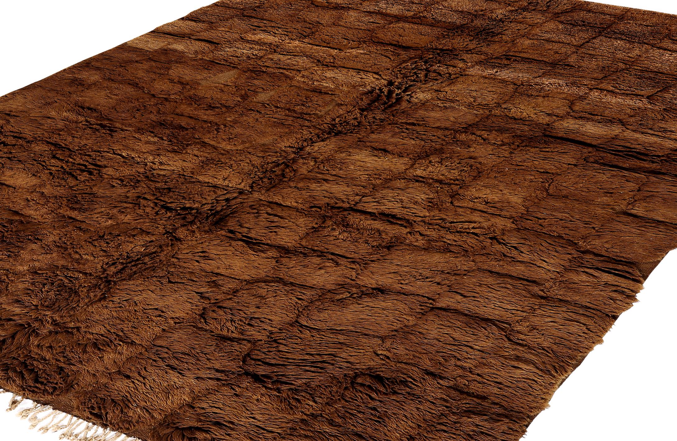 Ce tapis marocain contemporain est tissé à la main à partir de la laine naturelle la plus fine et présente un motif quadrillé richement texturé dans des tons chauds de marron terreux. Fabriquée par des artisans qualifiés, cette pièce incarne
