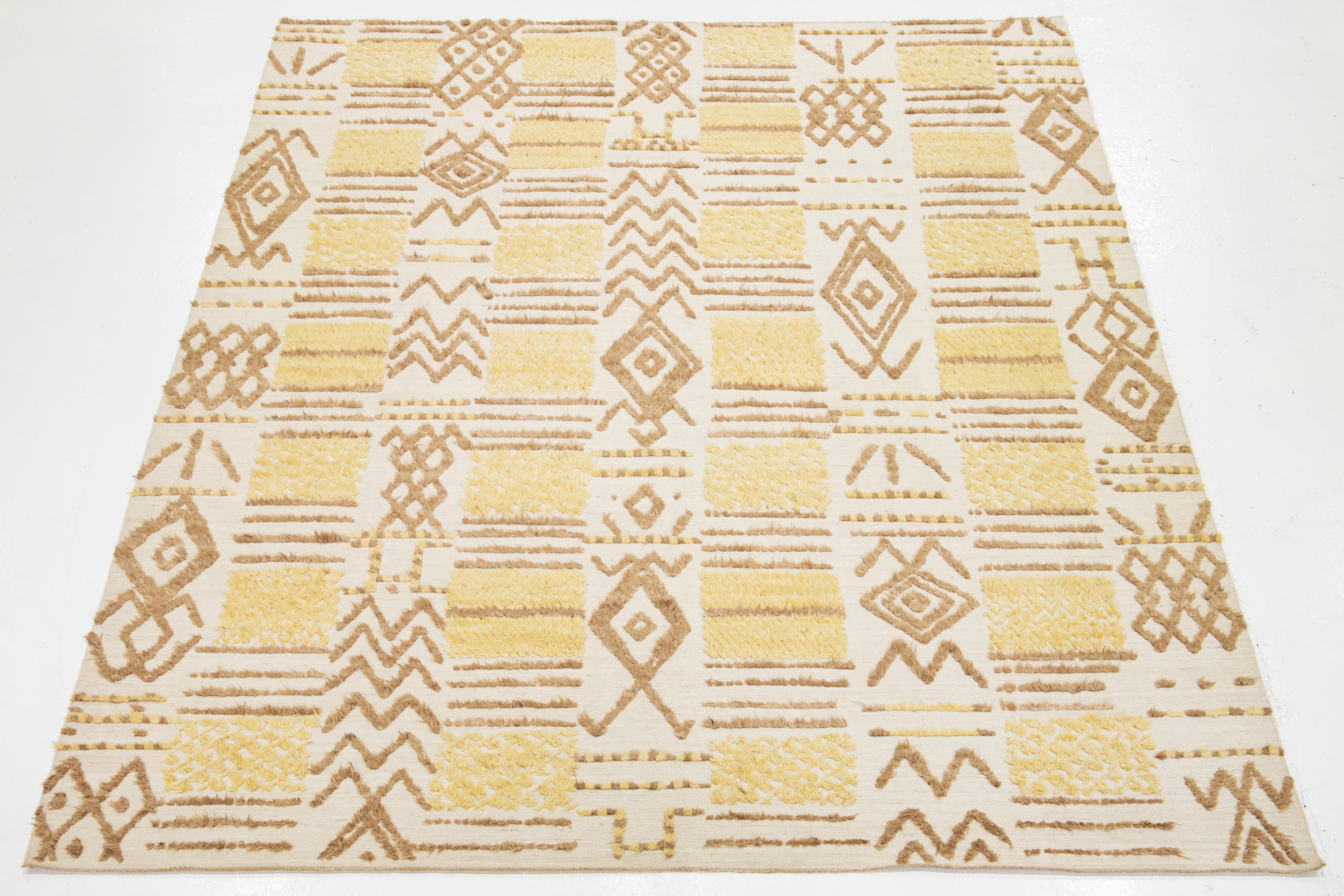 Questo tappeto in lana in stile marocchino, realizzato a mano e contemporaneo, presenta uno splendido sfondo beige che fonde perfettamente l'artigianato tradizionale con moderni elementi di design tribale nei toni del giallo e del marrone.

Questo