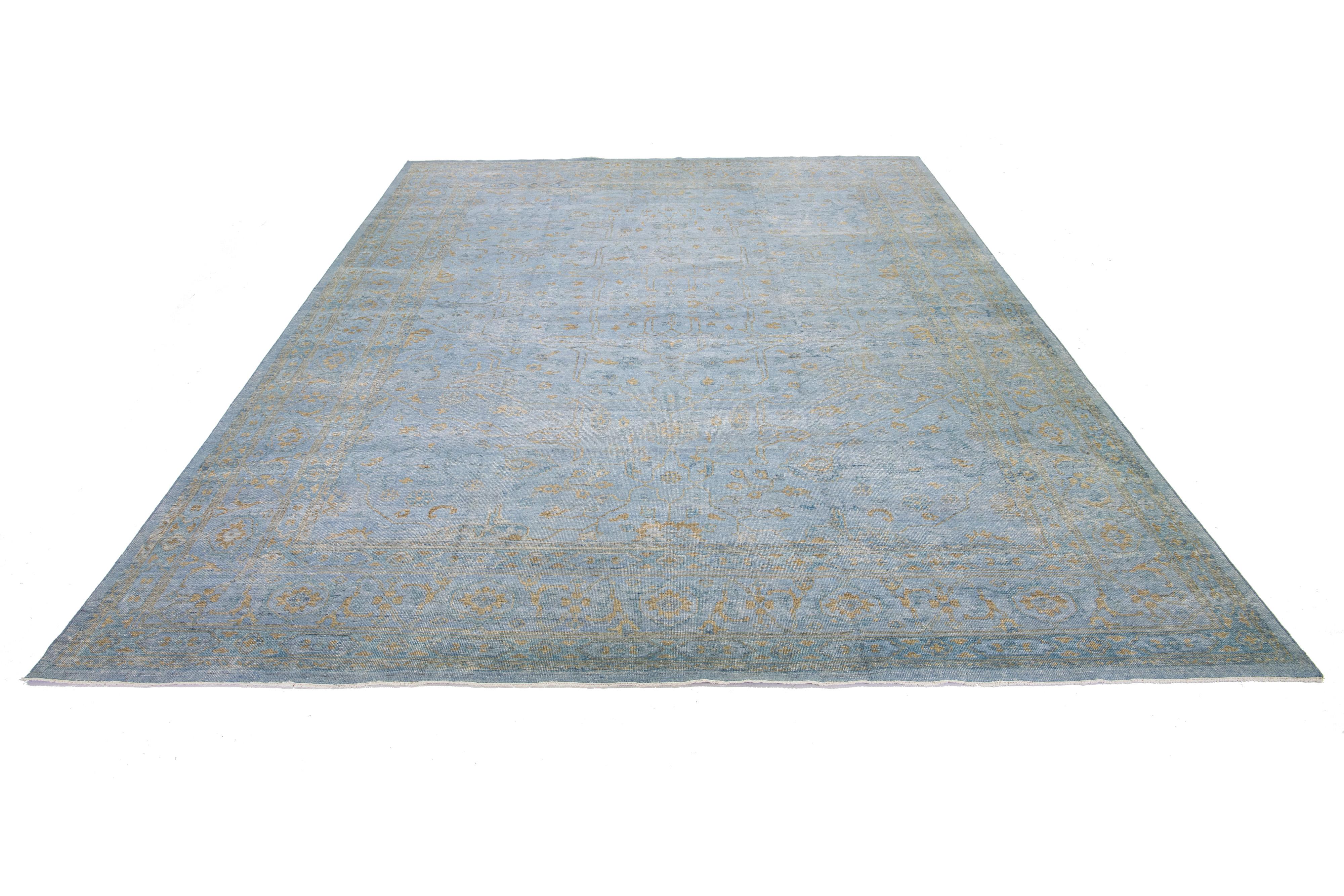 This Oushak rug is hand-knotted with a blue field. This mid-century modern-style rug has an allover golden floral design. 

This rug measures 11'9