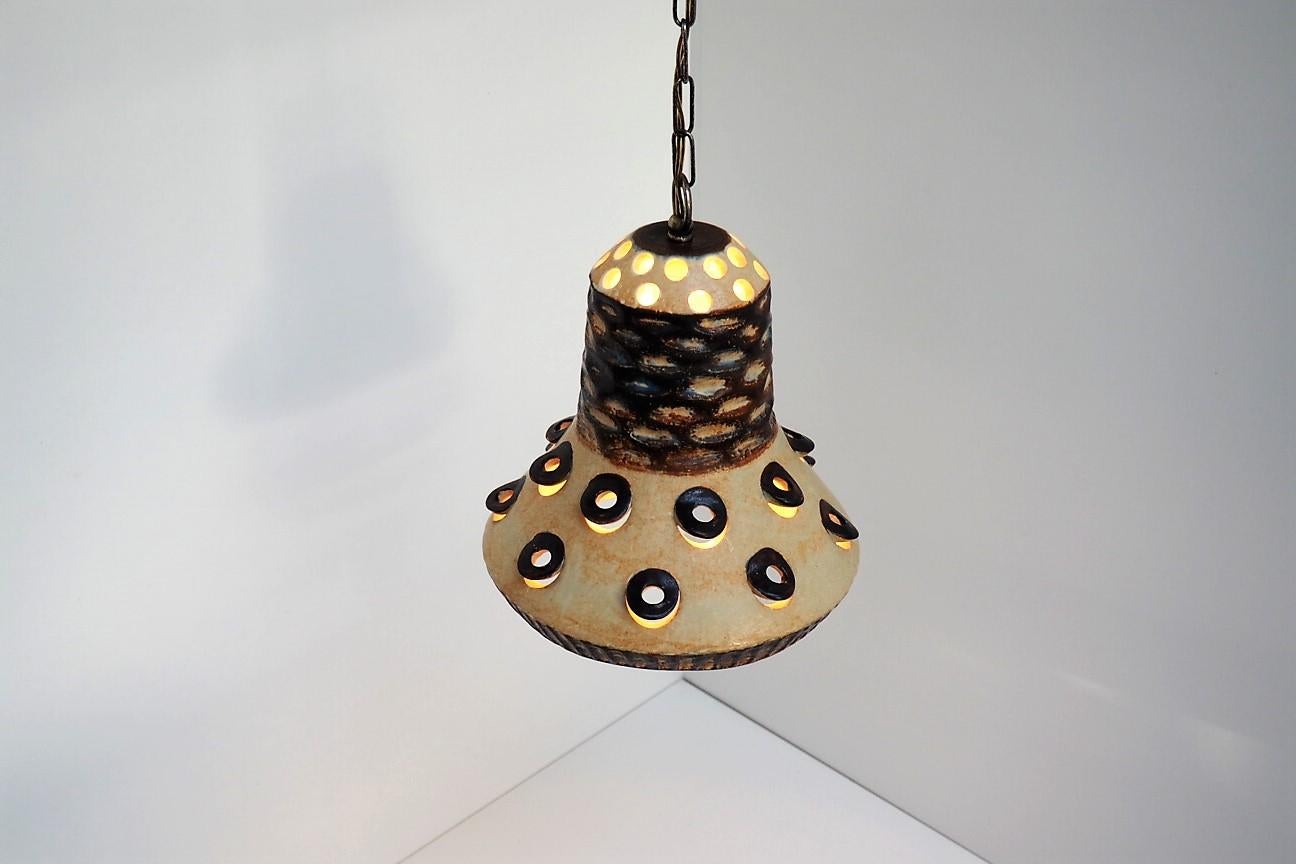 Handmade Danish ceramic pendant made in yellow, blue and brown glaze in the 1970s.

The pendant has a decorative hole pattern which appears beautifully when the light is on.

The pendant hangs in a matal chain including a gold colored plastic