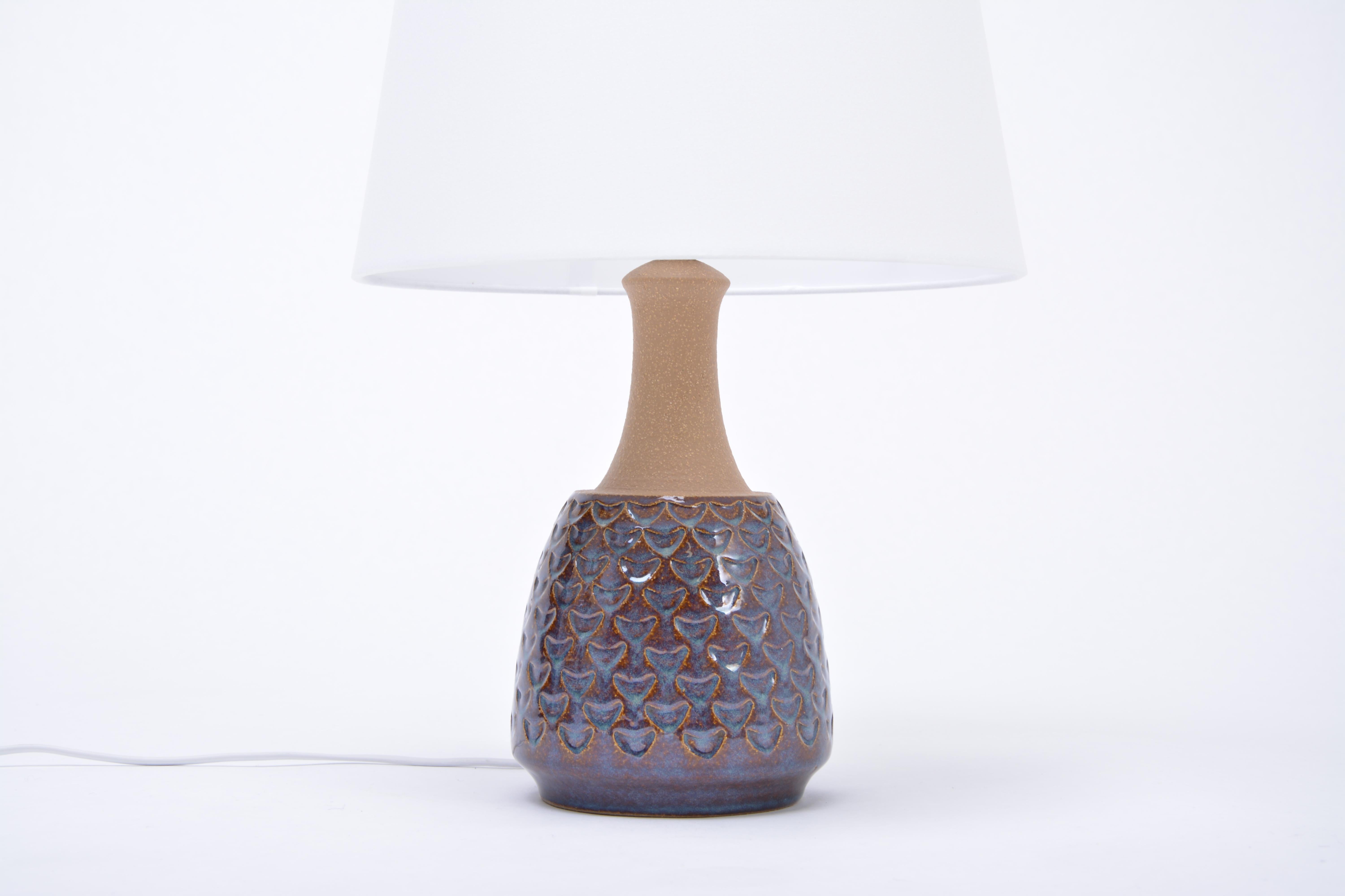 Handmade Danish Mid-Century Modern Stoneware lamp by Soholm
Table lamp handmade of stoneware with ceramic glazing in tones of blue. Graphical pattern to the base of the lamp. Produced by Danish company Soholm. The lamp has been rewired for European
