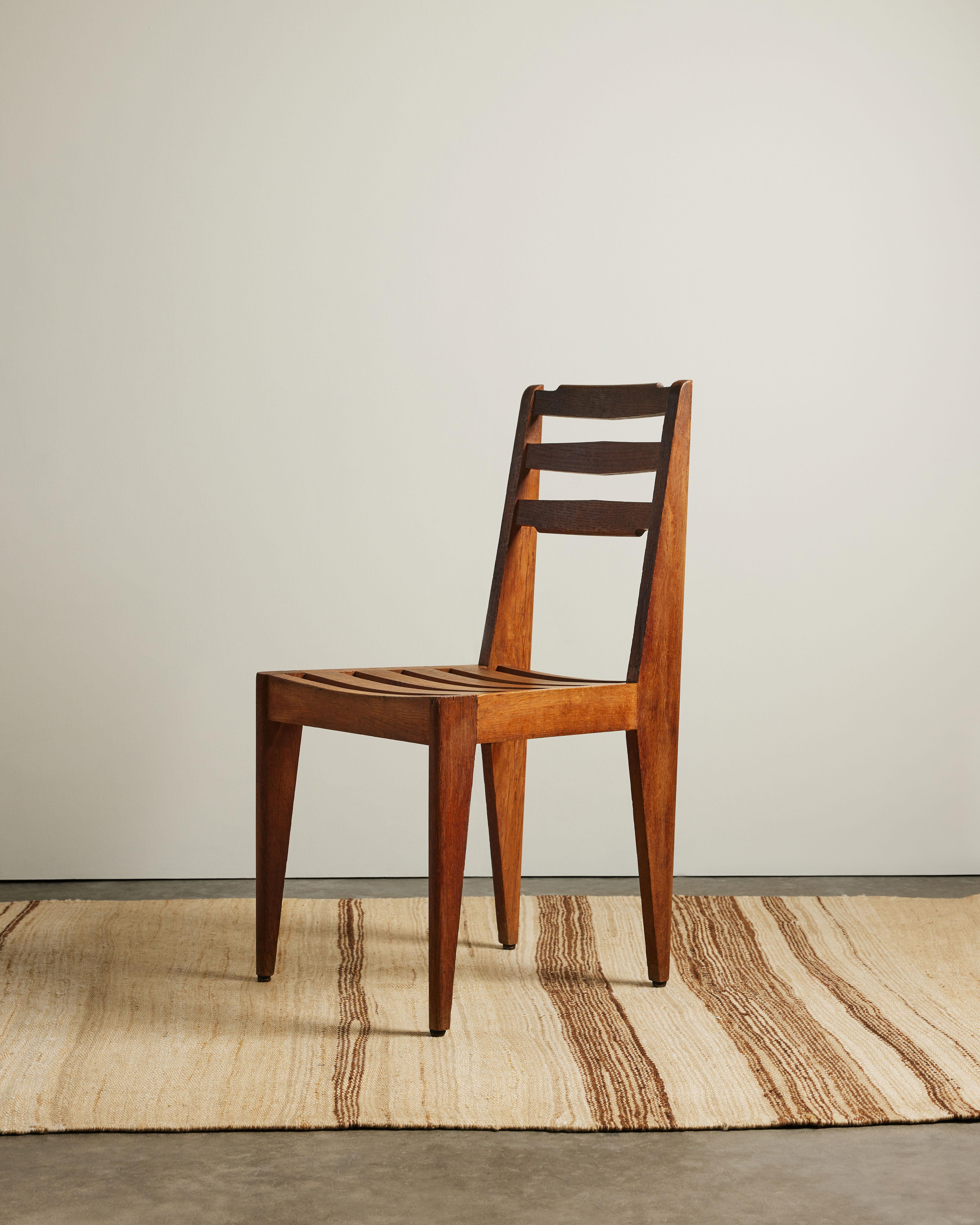 This handsome chair consists of a solid hardwood construction, tapered legs, and slatted seat and backrest. The chair has been lightly refurbished to ensure structural stability while preserving its character + material integrity.