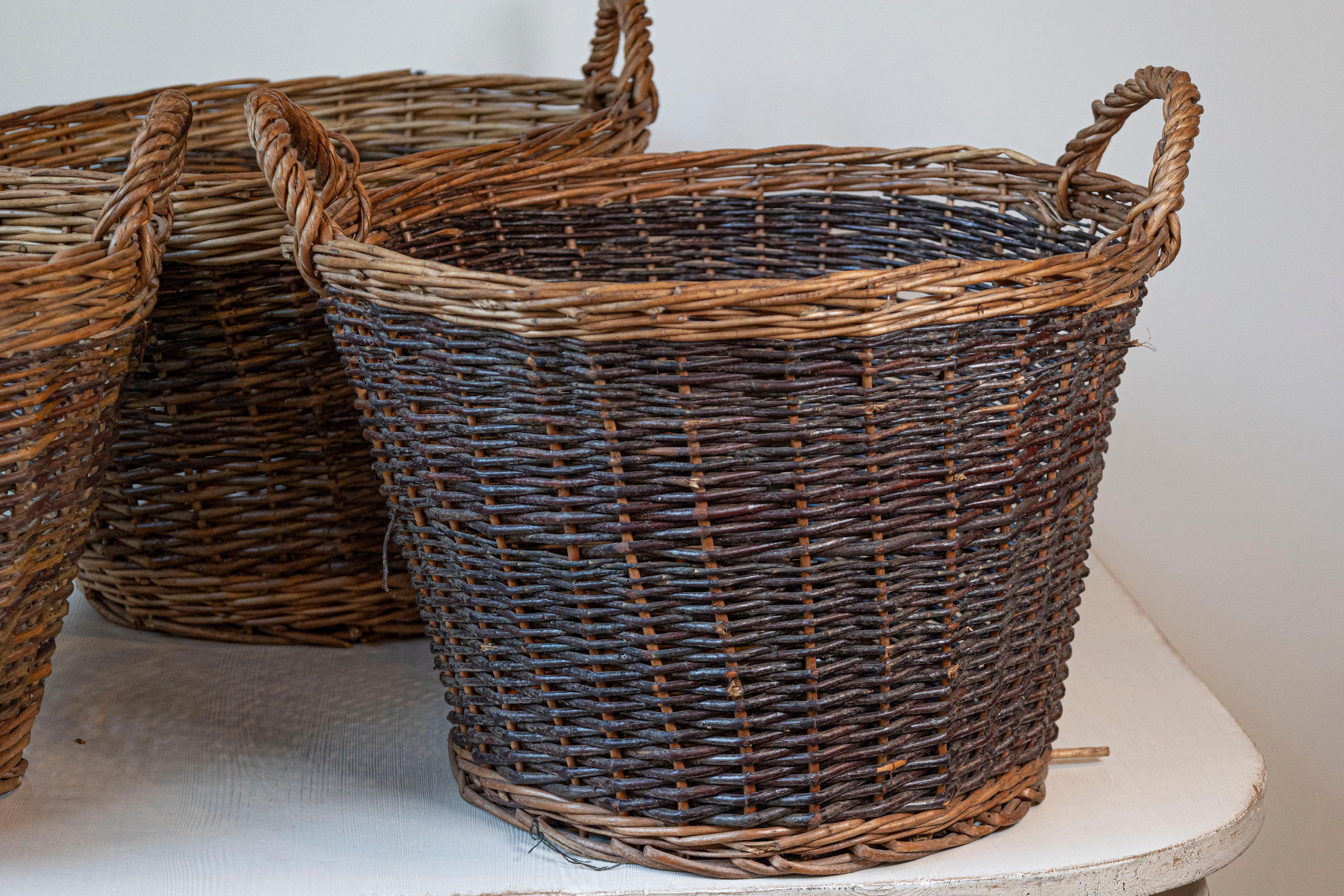 Three English wicker baskets with double handles, priced and sold each. Step into the world of English craftsmanship with these exquisite 20th Century wicker baskets, sourced from a private estate in Devon. These baskets, known for their robust