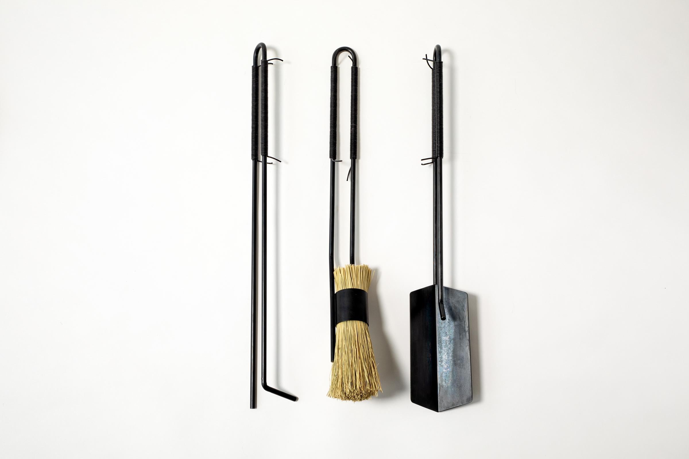 Outils modernes pour la cheminée en acier laminé à froid noirci et cordon de cuir enveloppé à la main.  Chaque pièce est fabriquée à la main dans notre atelier de Newburgh, dans l'État de New York.

L'ensemble comprend un tisonnier, une pelle, une