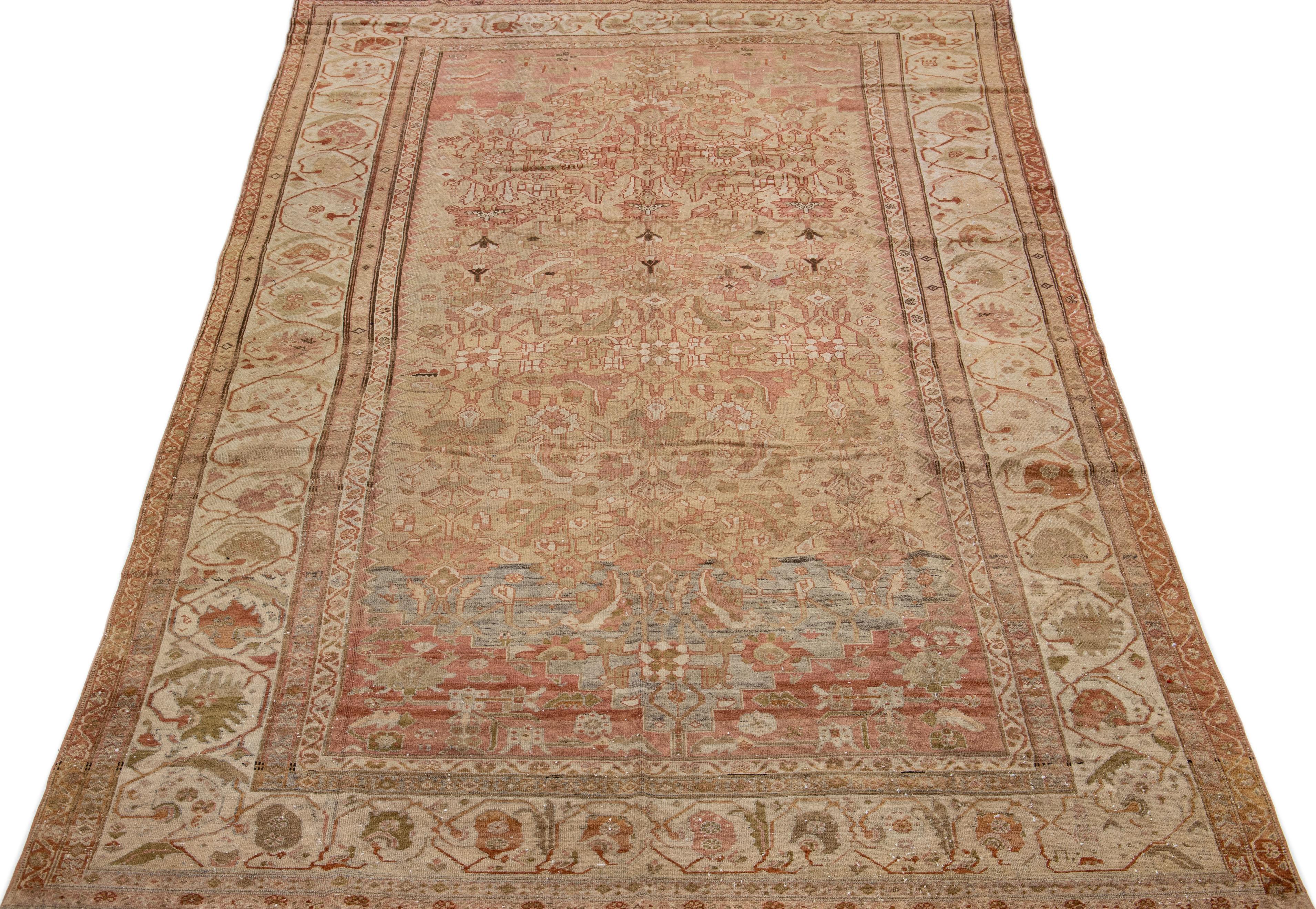 Beautiful antique Malayer hand-knotted wool rug with a tan color field. This Persian rug has peach and blue accents in a gorgeous traditional all-over floral design.

This rug measures 7'4