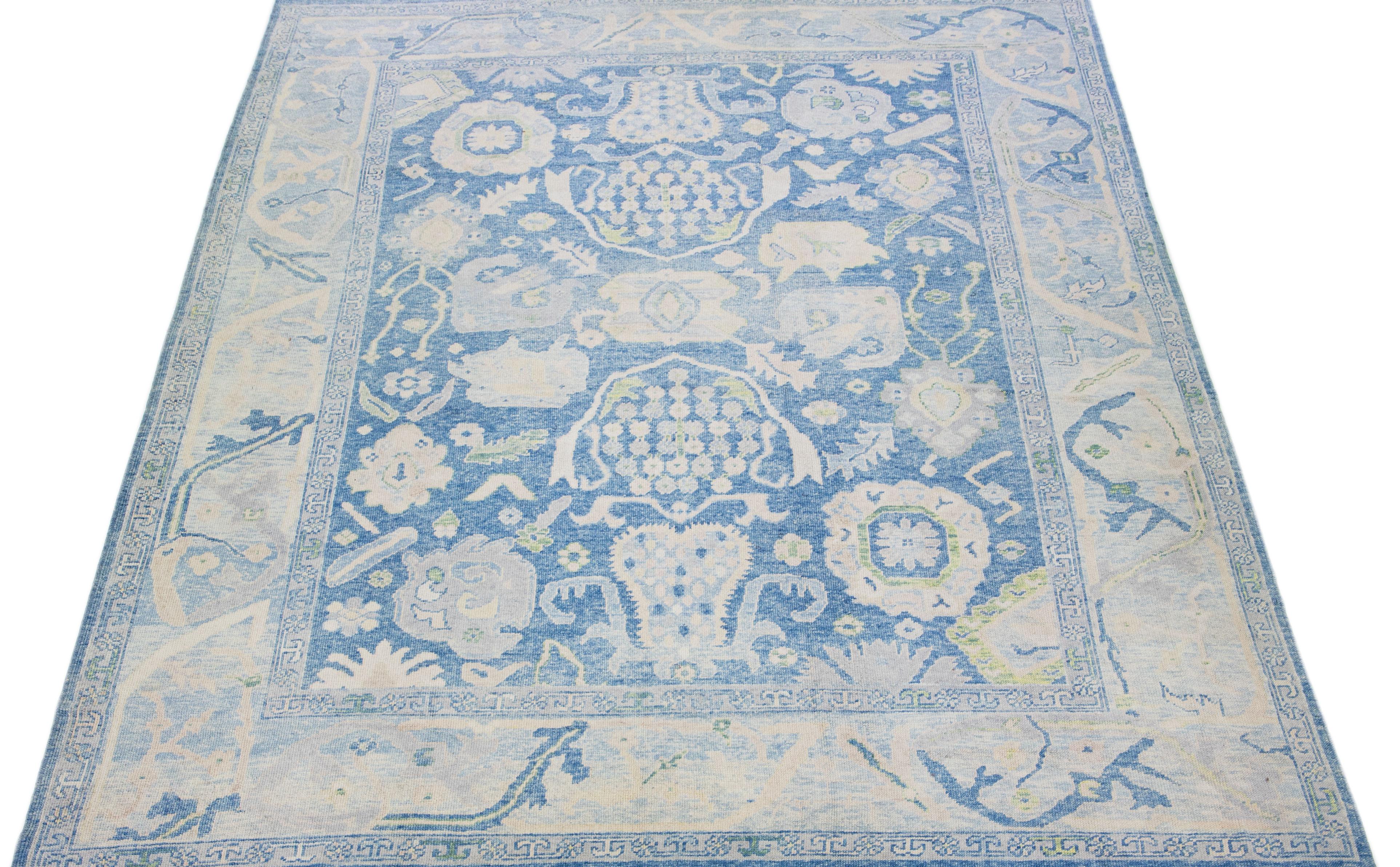 Beautiful modern Oushak hand-knotted wool rug with a blue color field. This Turkish Piece has beige, gray, and green accent colors in a gorgeous all-over floral design.

This rug measures: 10'5