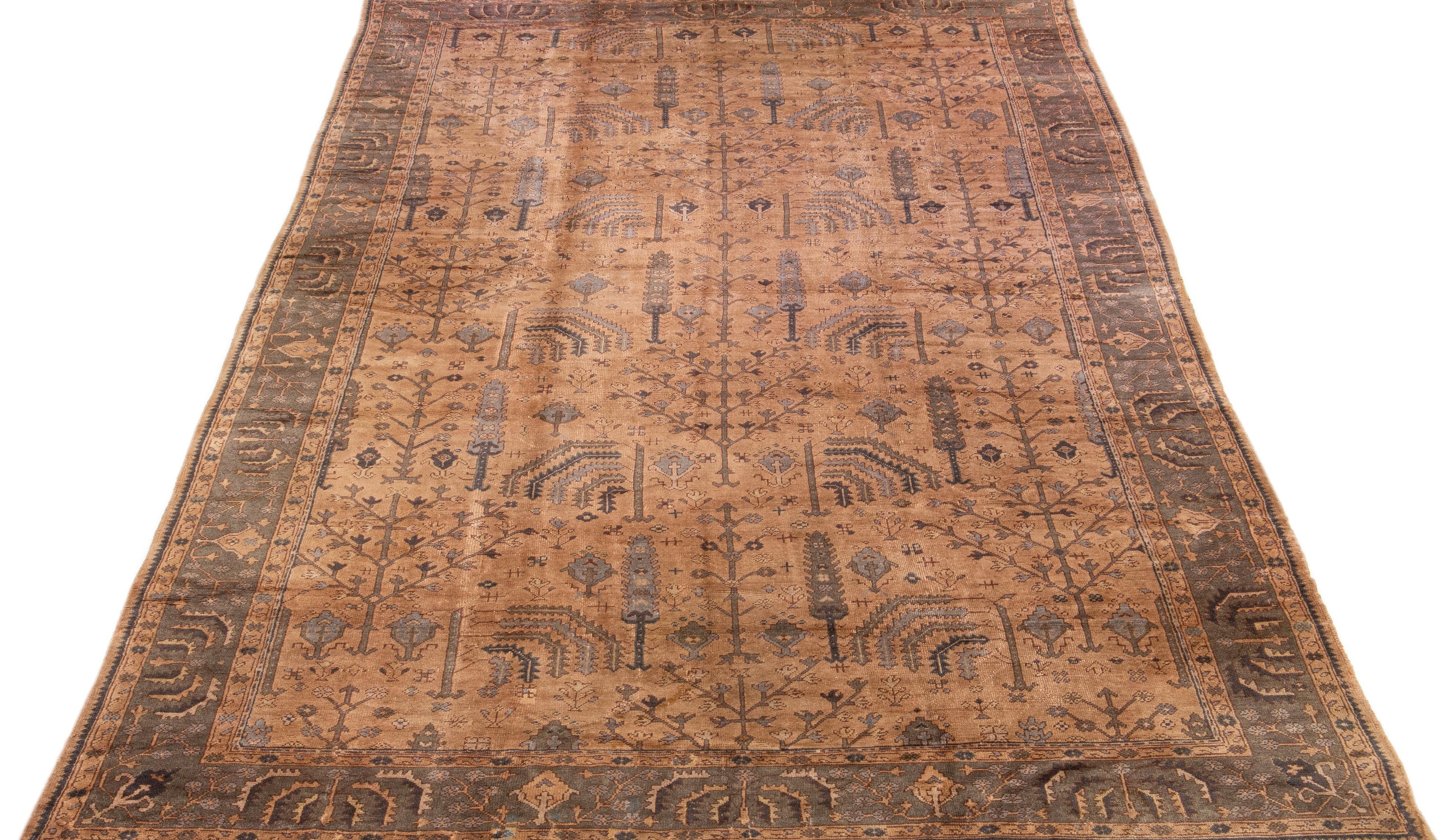 Beautiful Antique Oushak hand-knotted wool rug with a tan field. This Turkish rug has a gray-designed frame with blue and beige accents in a gorgeous all-over floral pattern design.

This rug measures: 10'8