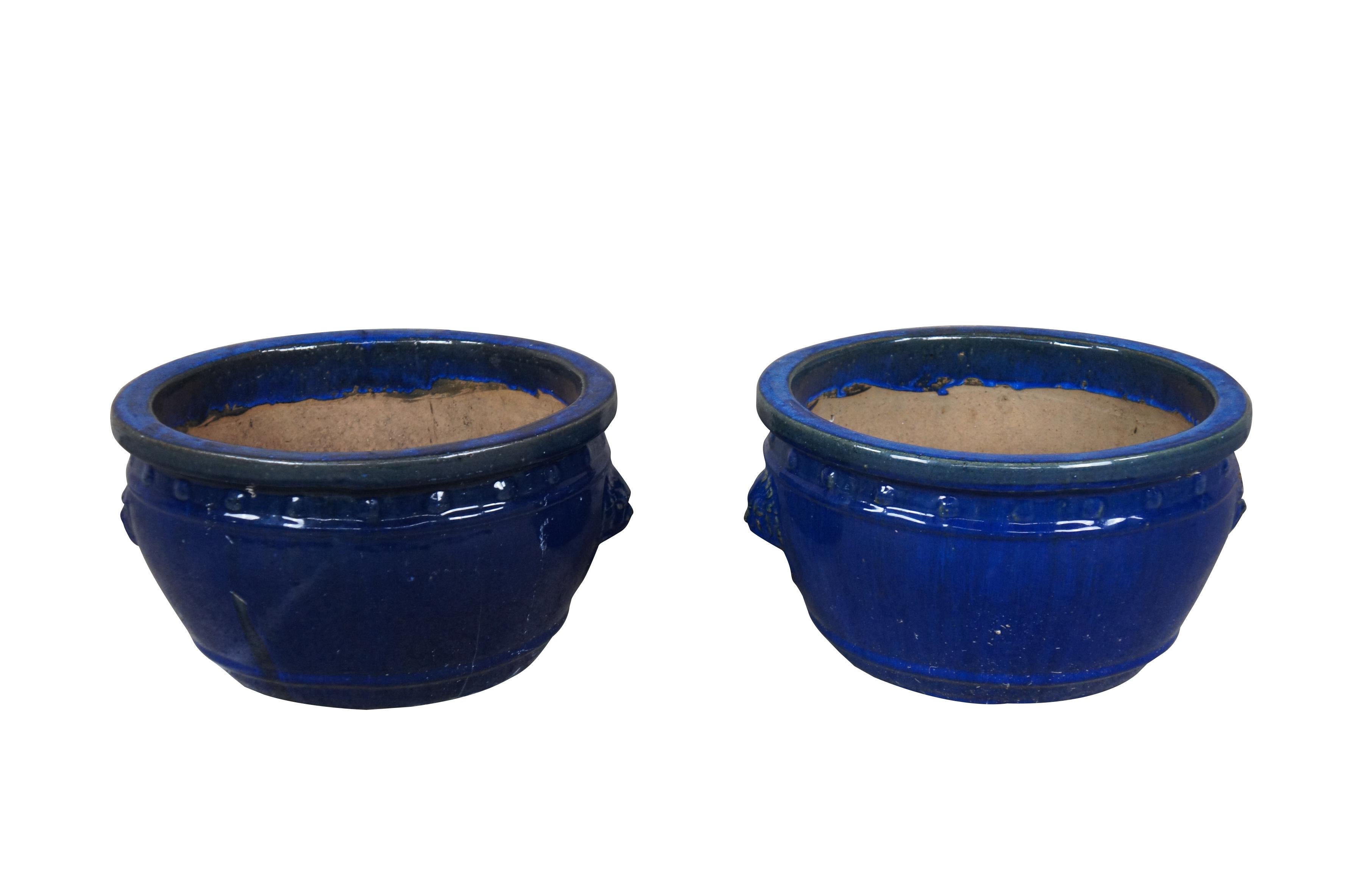 2 handgefertigte blaue Keramik-Urnen.  Blau glasiert mit Löwenköpfen und Klopfern.  Mit erhabenen Punkten unter dem oberen Rand und einem Tropfloch im Boden.

Abmessungen:
16 