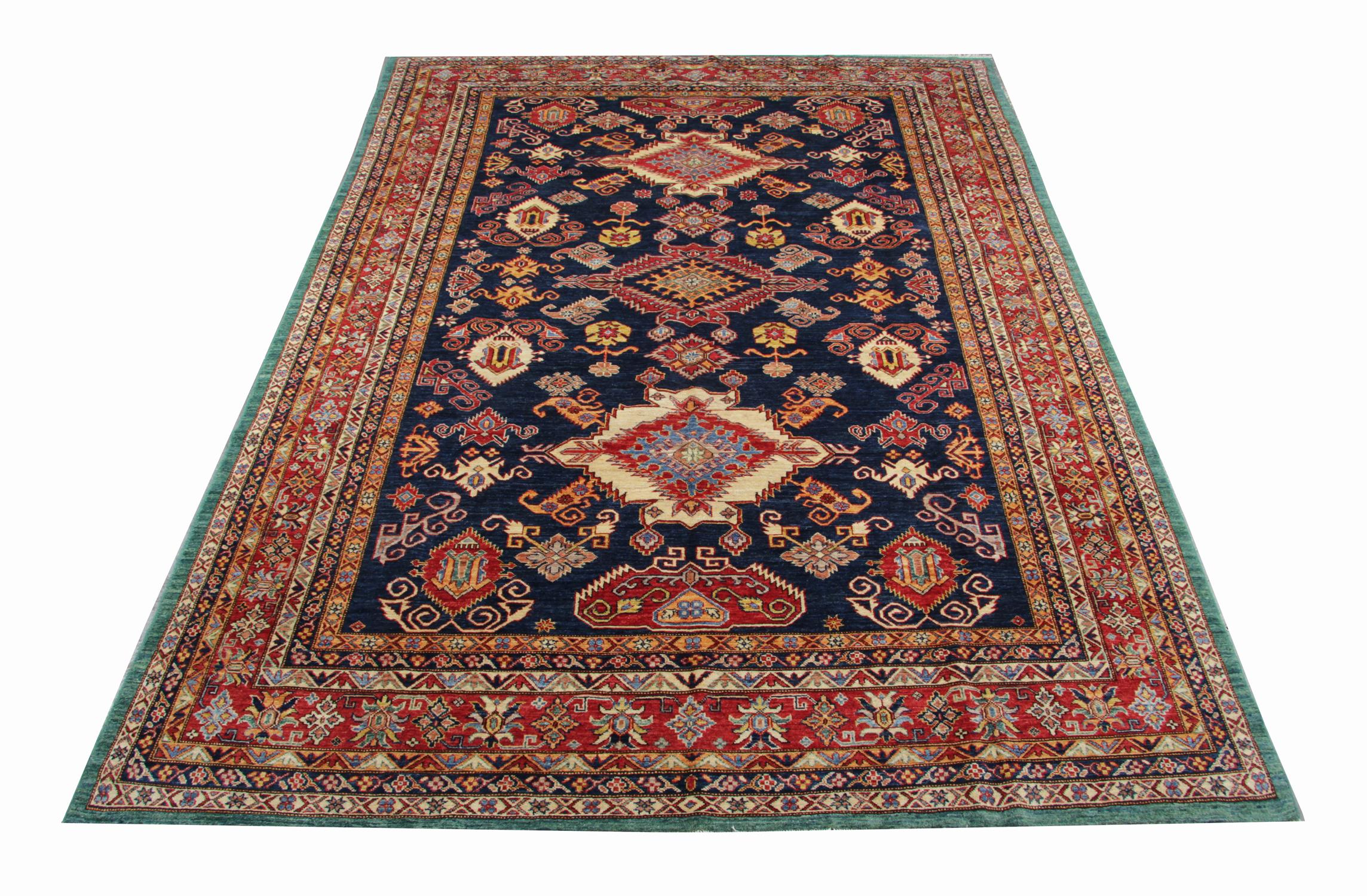 A beautiful new traditional Afghan Kazak rug features a conventional tribal medallion design woven in beige, navy blue and green accents through the centre on a red field. The design is then finished with a highly-detailed repeat pattern border that
