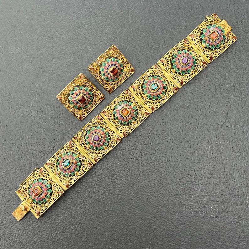 Das chinesische Exportarmband im Vintage-Stil ist ein wahres Kunstwerk mit filigranen, vergoldeten Sterlingsilberplatten. Jedes Paneel ist mit edelsteinfarbenen Glascabochons in Lünettenfassung und zarten Emailleblumen verziert, die ein zeitloses,