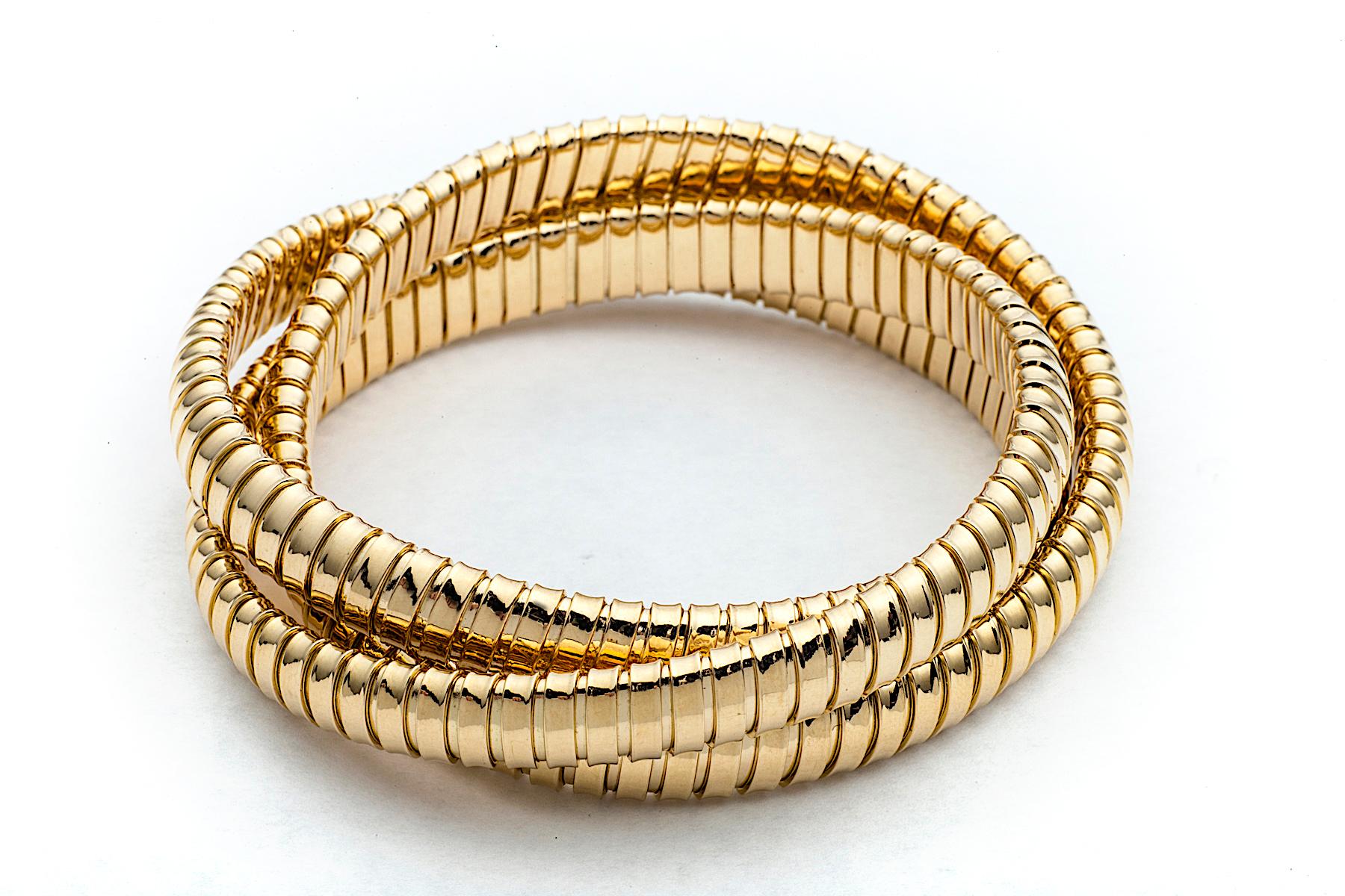 With a timeless but modern style, this chic intertwined three strand 9mm tubogas rolling bangle bracelet was originally inspired by the flexible automotive gas tubing of the 1920’s. Translated into luxurious 18 karat yellow gold and easily stacked