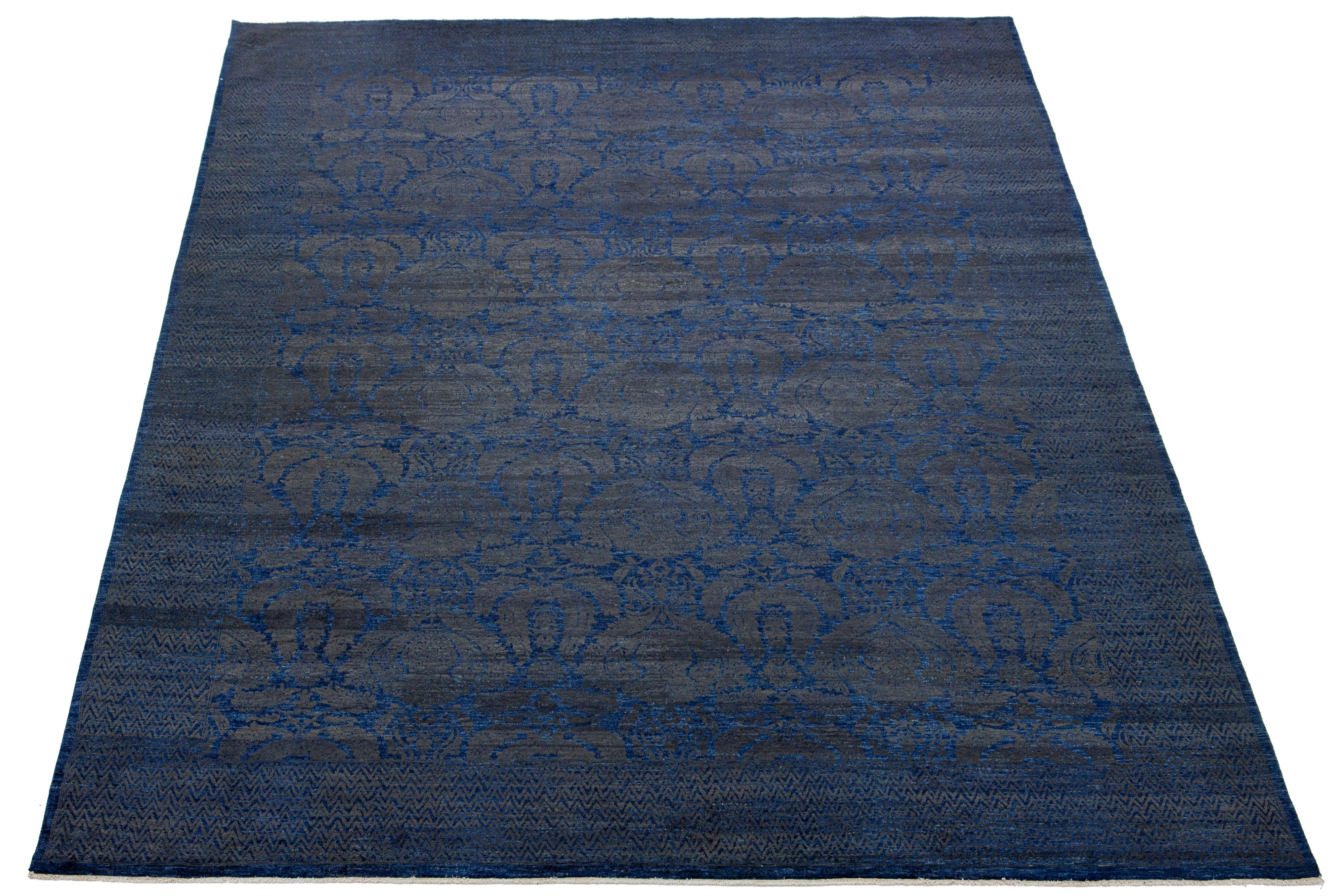 This oversized hand-knotted wool rug showcases a dark gray field. It's designed with a stunning allover floral pattern and accented with navy blue hues in a Transitional allure.

This rug measures 9'10