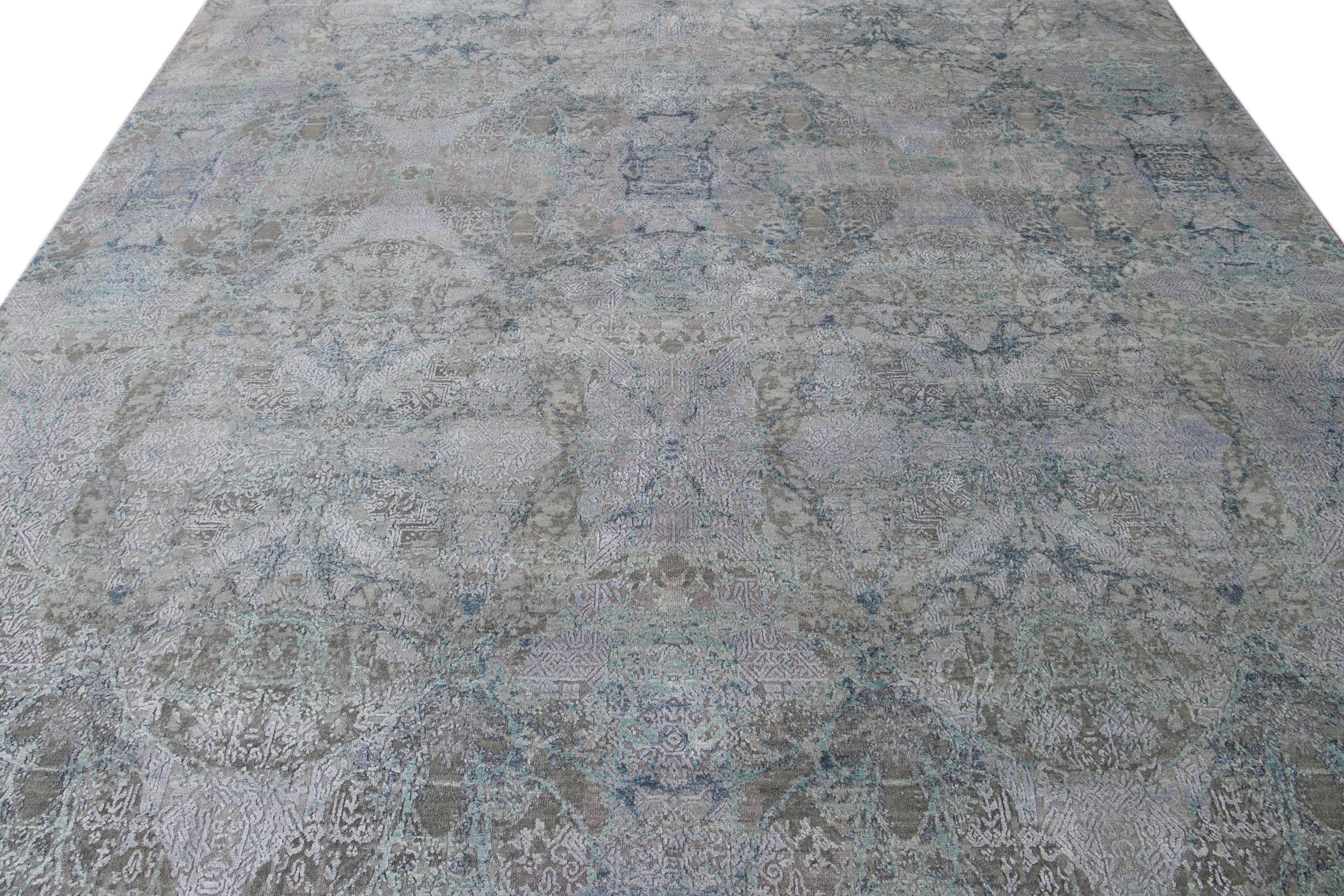 This modern rug features a refined combination of wool and silk, highlighting a mesmerizing abstract pattern embellished with graceful blue, silver, and green hues, artfully encompassing a captivating dark gray backdrop.

This rug measures 8'11