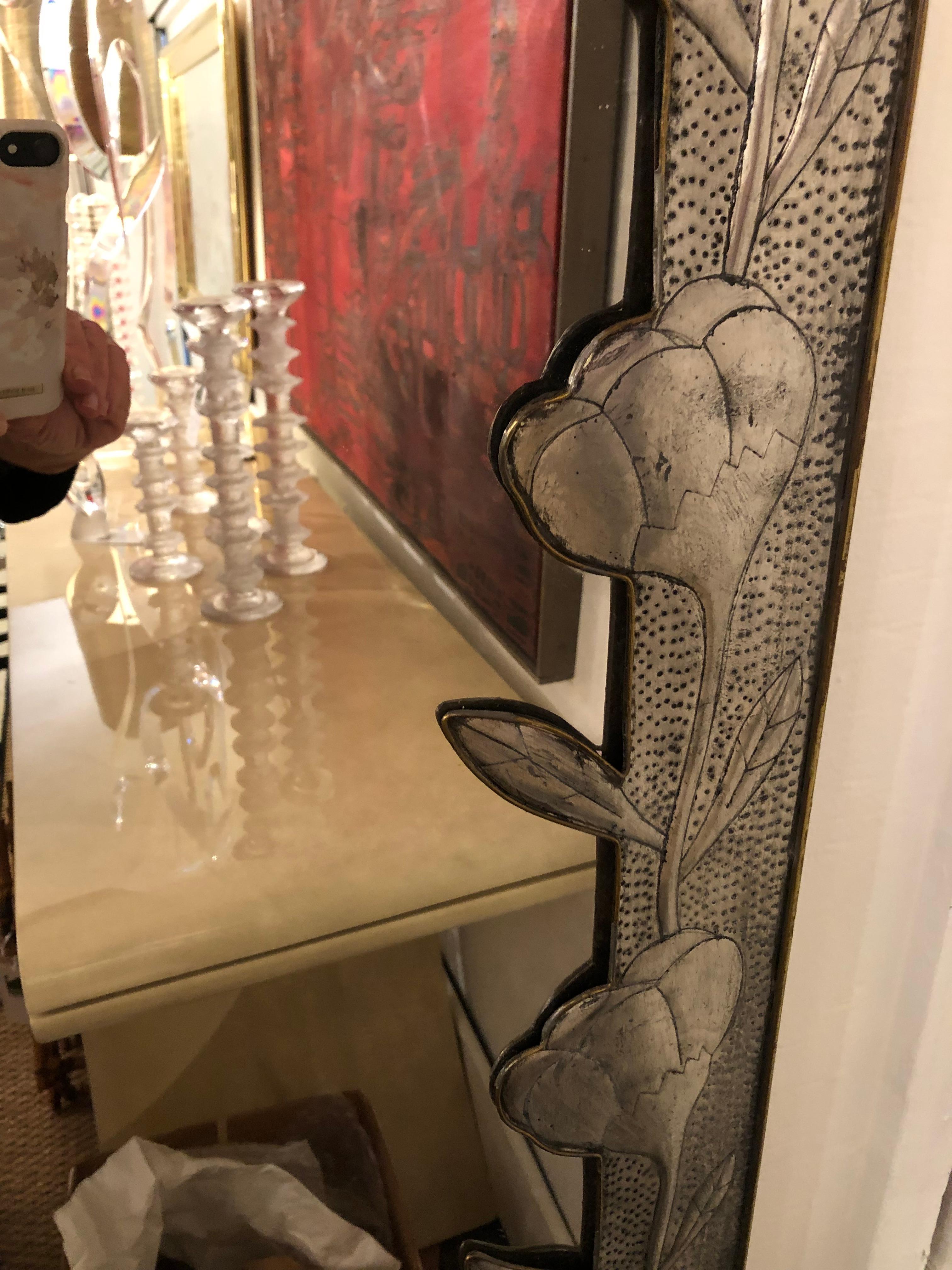 Wonderful imaginative handmade Mexican mirror having a hammered metal and brass frame with abstract flowers and a marvelous brass peacock that drapes across the upper left of the mirror. Signed lower right.