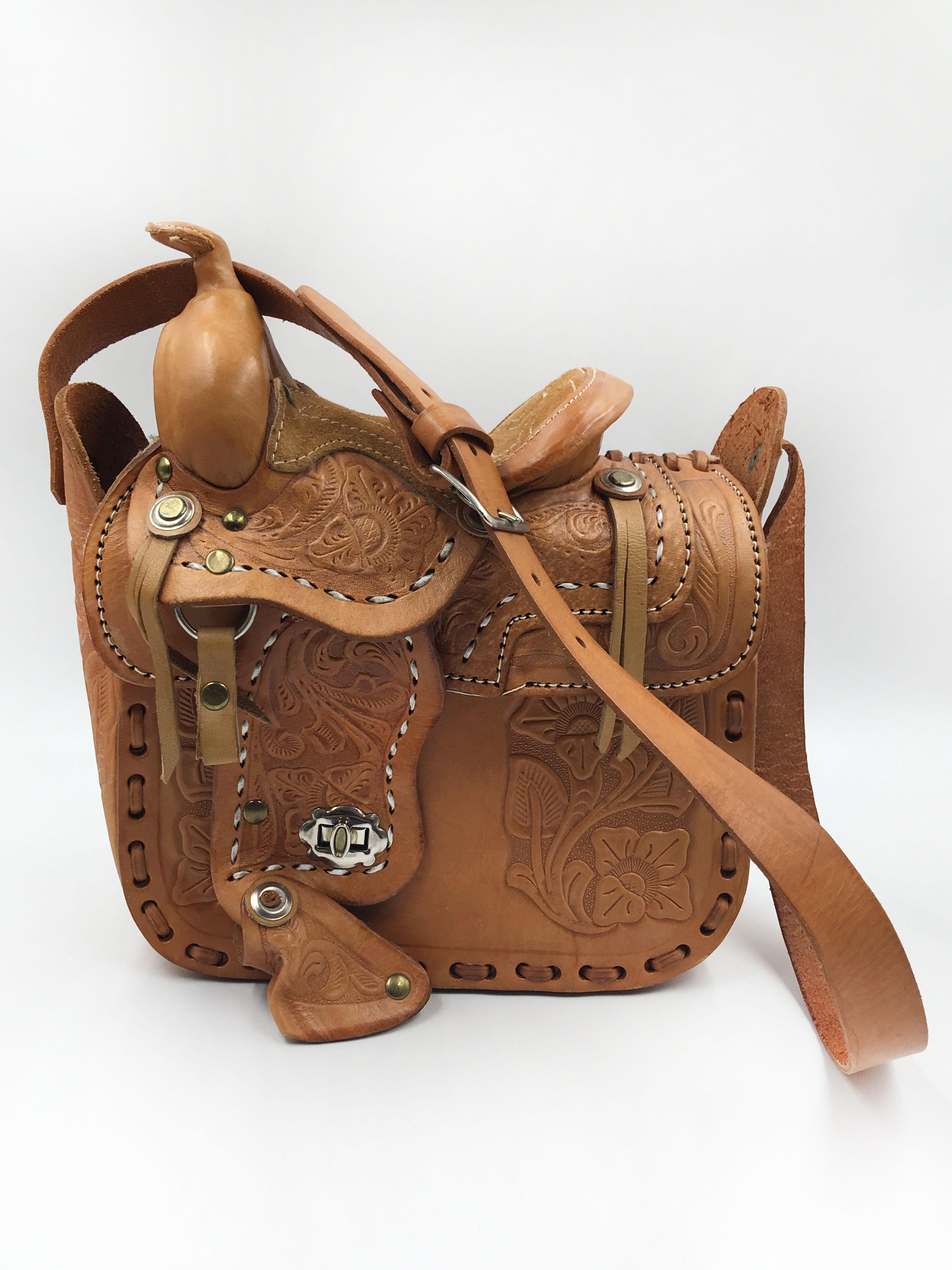 Handmade, Hand Tooled Mexican Leather and Sheepskin Saddle Shoulder Bag. Sheepskin lines the flap and inside the bag is no lining. Never used and leather has never been oiled. Turn style closure. Strap is adjustable with silver buckle. Holes are 1