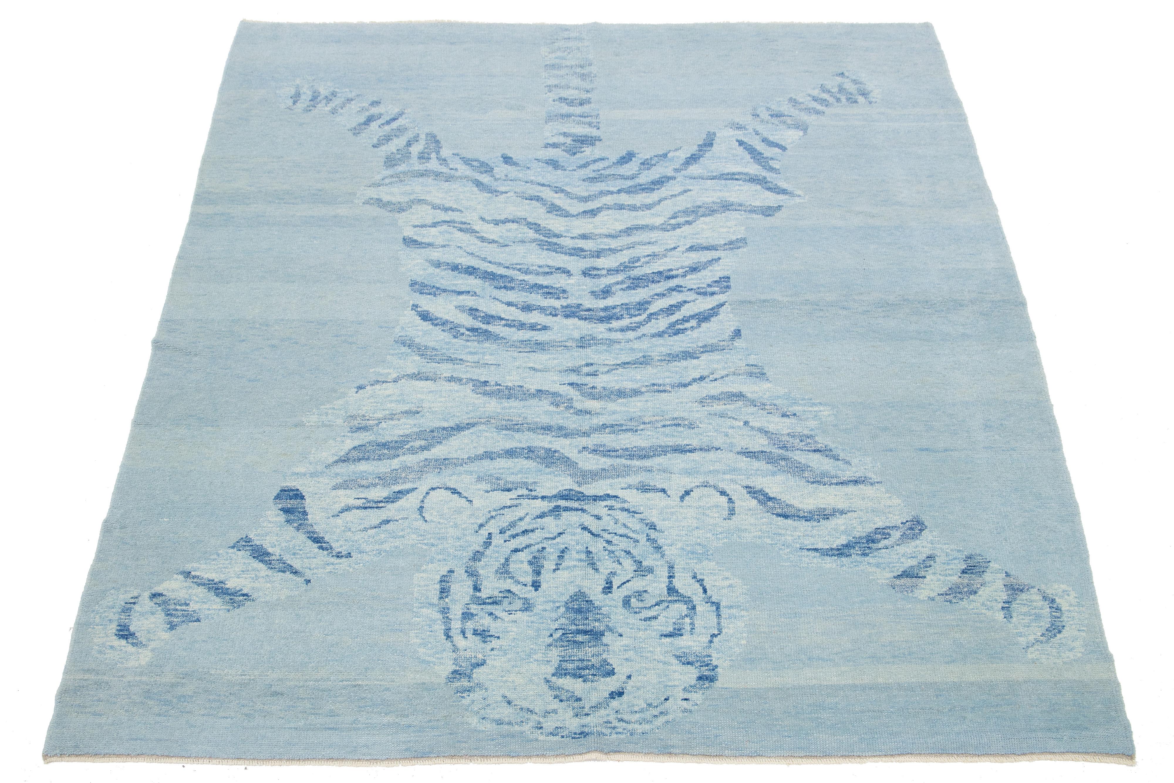 Ce magnifique tapis turc en laine de style Art déco présente un champ bleu avec des accents beiges et un superbe motif pictural représentant un tigre.

Ce tapis mesure 6'3