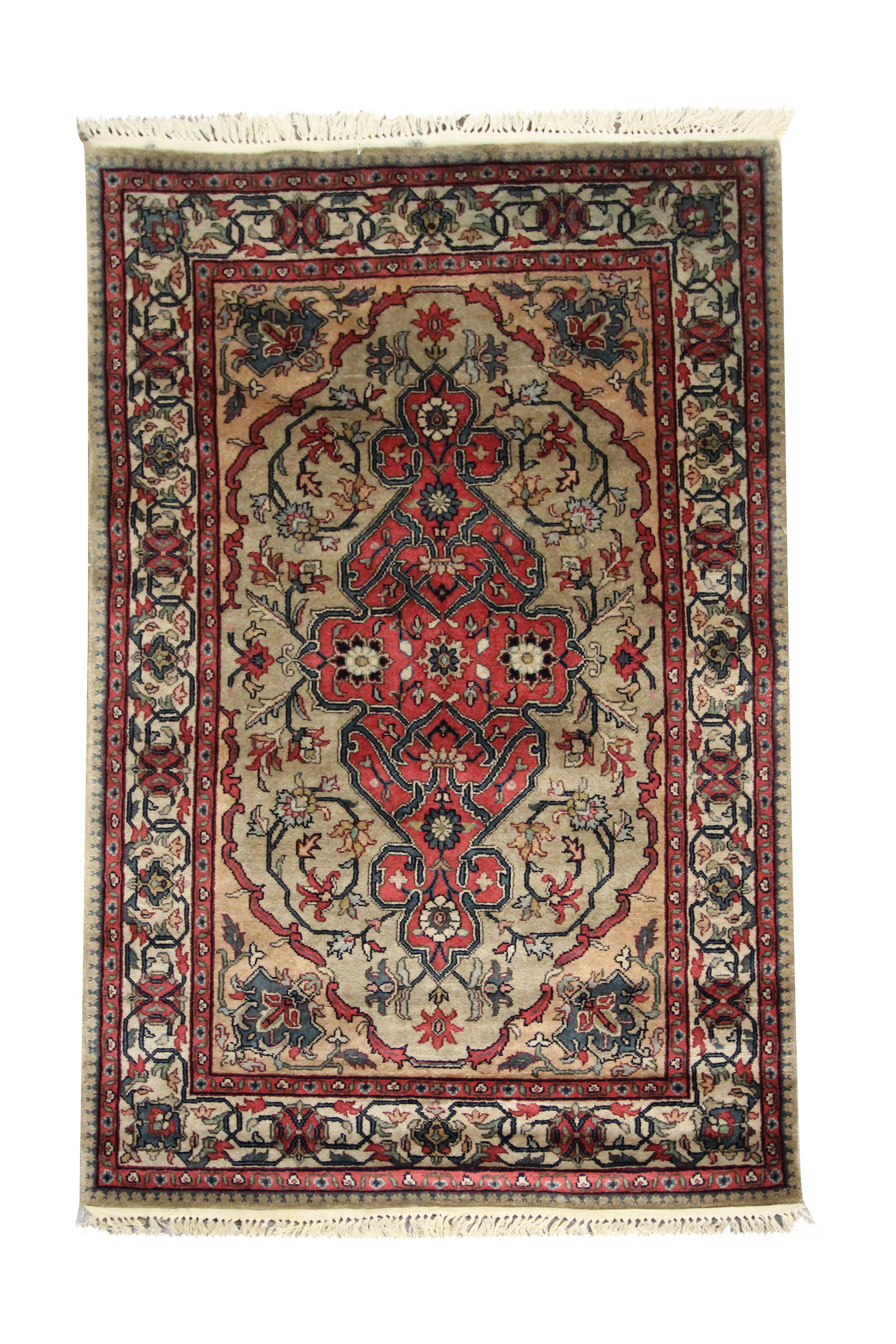 This bold wool rug is an Indian carpet woven in the early 2000s. The design has been intricately woven and features a detailed symmetrical pattern woven in accents of green, red, beige and blue. Decorated with intricate hook motifs and geometric
