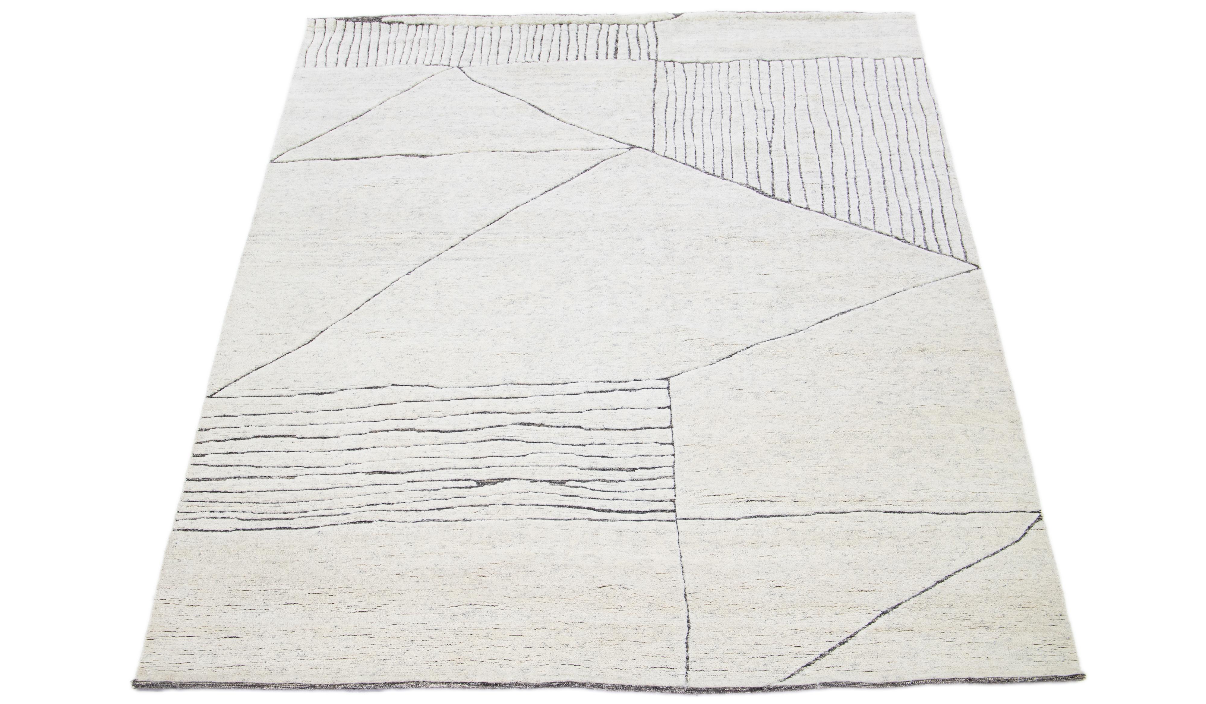 This luxurious wool rug features a timeless Moroccan pattern in a contemporary abstract Minimalist style, utilizing Ivory tones to create a sleek and modern look. It is crafted using traditional hand-knotting techniques, ensuring exceptional quality