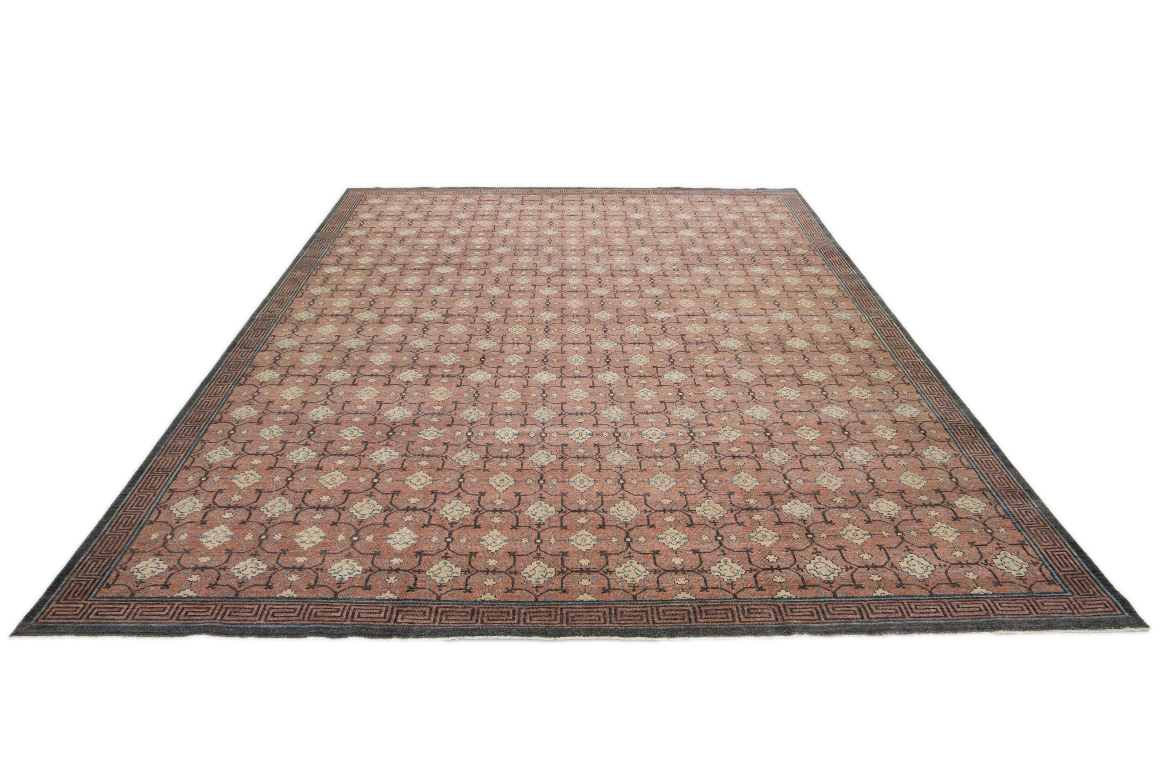Ein Khotan-Wollteppich in einem pfirsichbraunen Farbfeld mit miteinander verbundenen Rosettenmustern. Dieses handgeknüpfte moderne Stück hat beige und graue Akzente, die das Design ergänzen.

Dieser Teppich misst 11'11