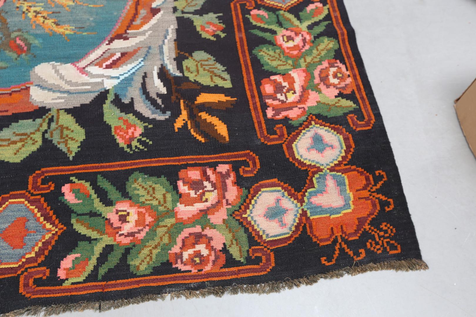 This luxurious antique floral rug is a Moldavian Kilim woven by hand in the 1940s. Elegantly woven roses flow through this design, woven asymmetrically to create a beautiful, eye-catching display. Featuring a deep brown background with green,