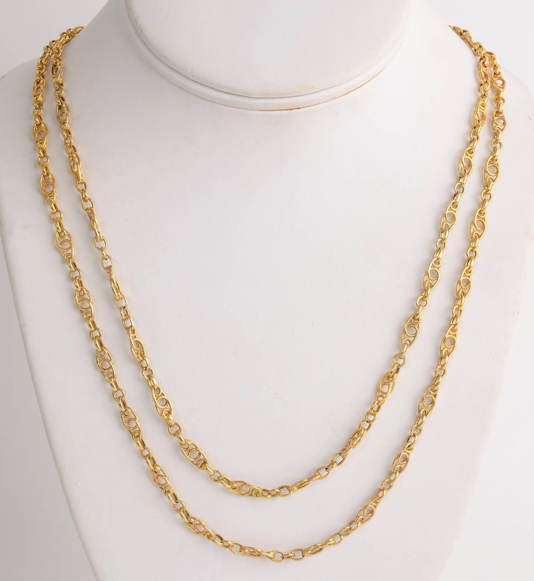 Finely made 18 karat gold chain necklace that is 61 inches in length. It has both a jump ring clasp and a watch chain clasp so it can be worn in multiple lengths. The links are overlapping ovals that form circles and curlicues. Each link is 3/16