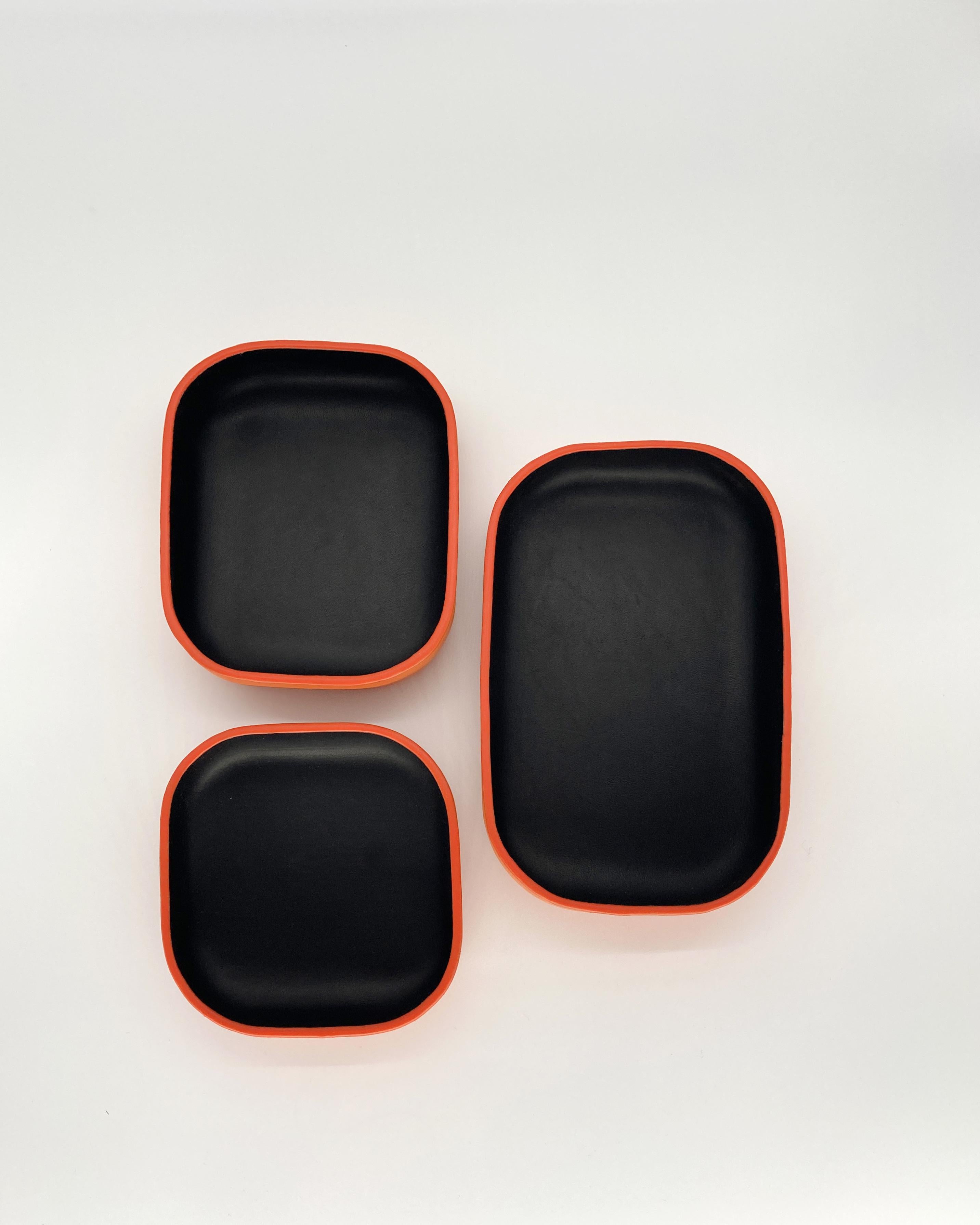 Cet ensemble de plateaux en cuir faits main, de couleur noire et orange, est parfait pour compléter la table de votre salle à manger ou comme pièce maîtresse dans votre salon. Le charme rustique rencontre la sensibilité du design artisanal