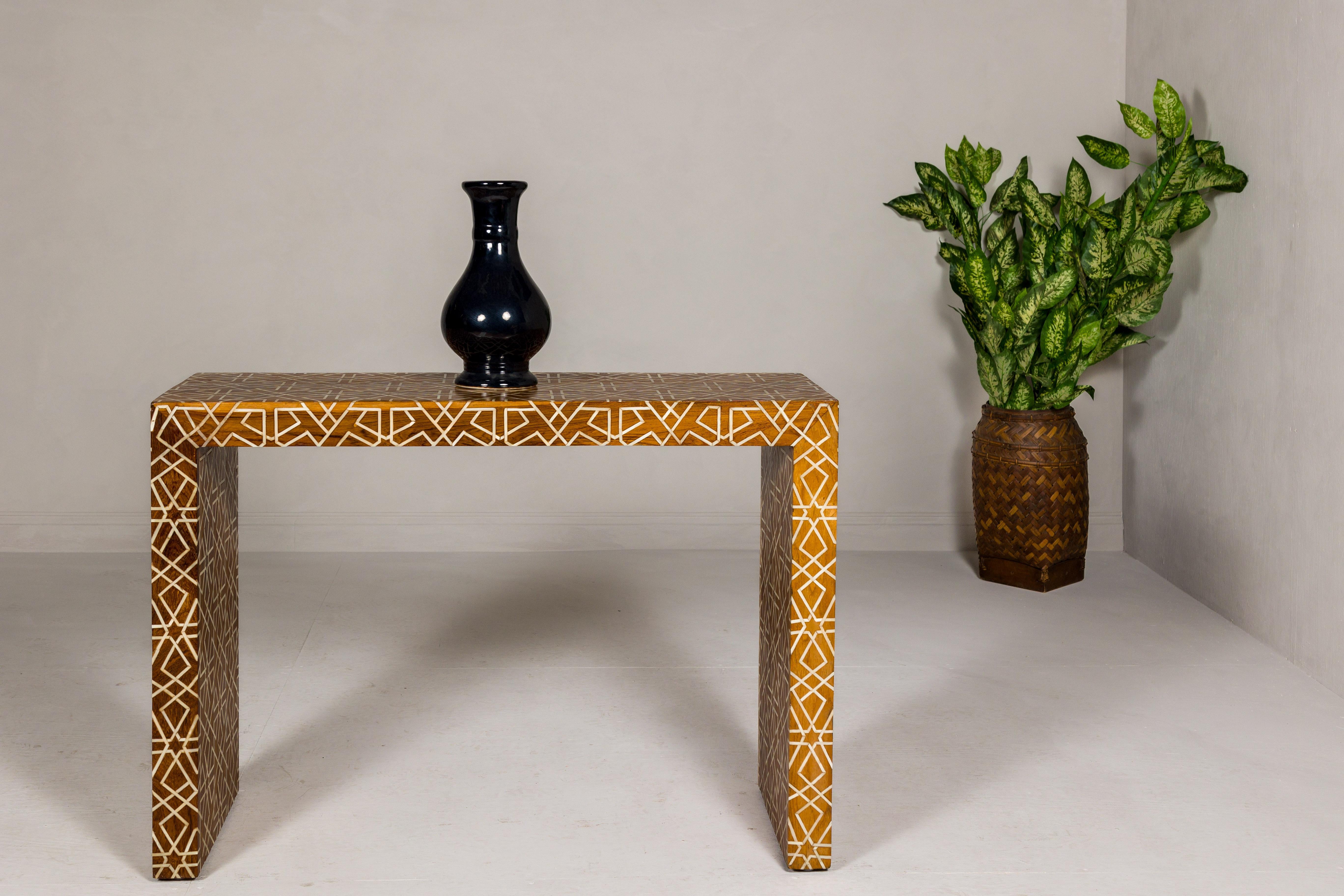 A handmade mango wood linear console table with geometric bone inlay. Capturing the essence of contemporary artistry and time-honored craftsmanship, this handmade mango wood console table is a true work of art. Intricate geometric bone inlay