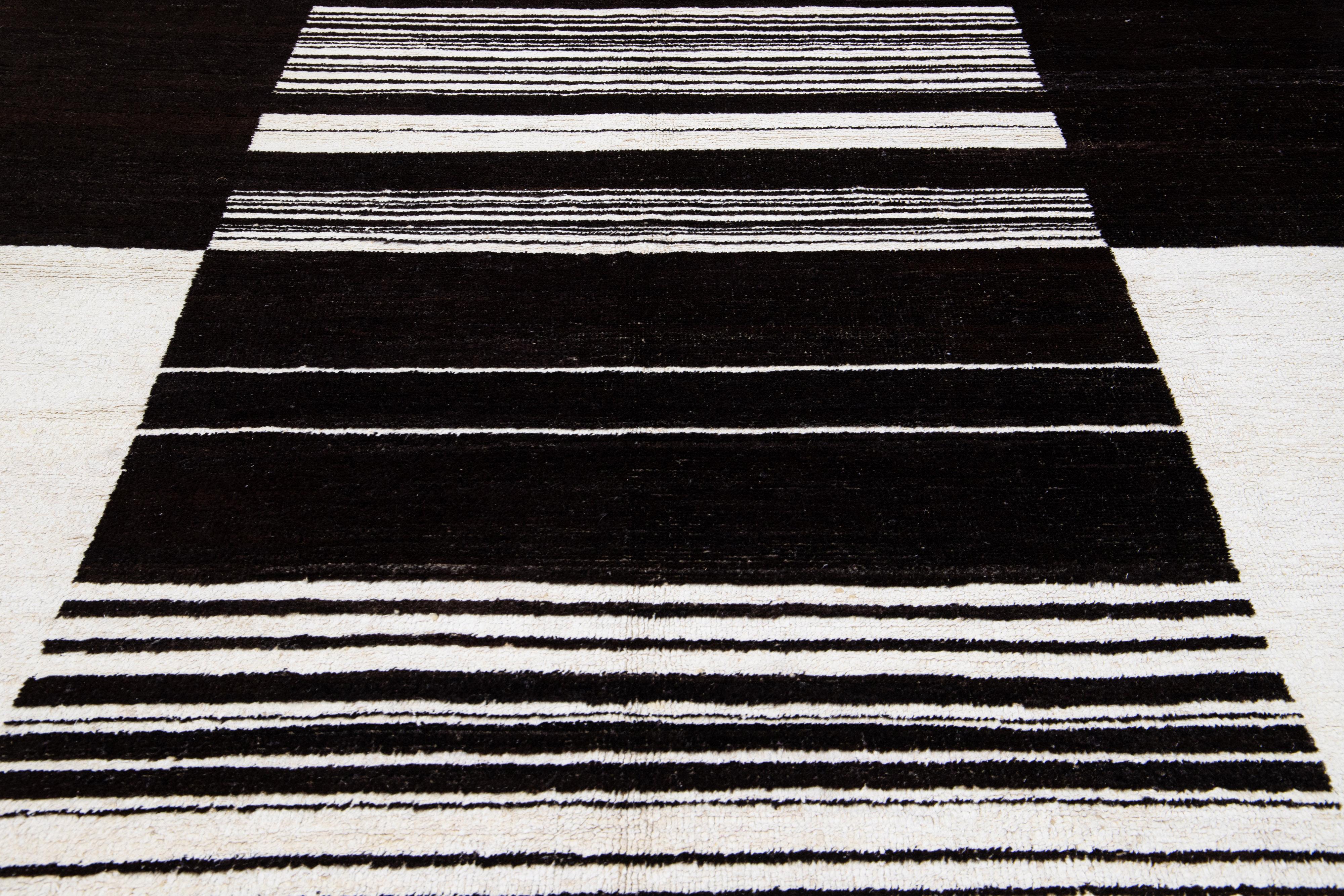 Dieser moderne marokkanische Wollteppich 9 x 12 ist aus hochwertiger Wolle handgeknüpft und wird mit fachmännischem Können hergestellt. Es zeichnet sich durch ein auffälliges weißes und schwarzes Farbfelddesign aus, das durch ein minimalistisches