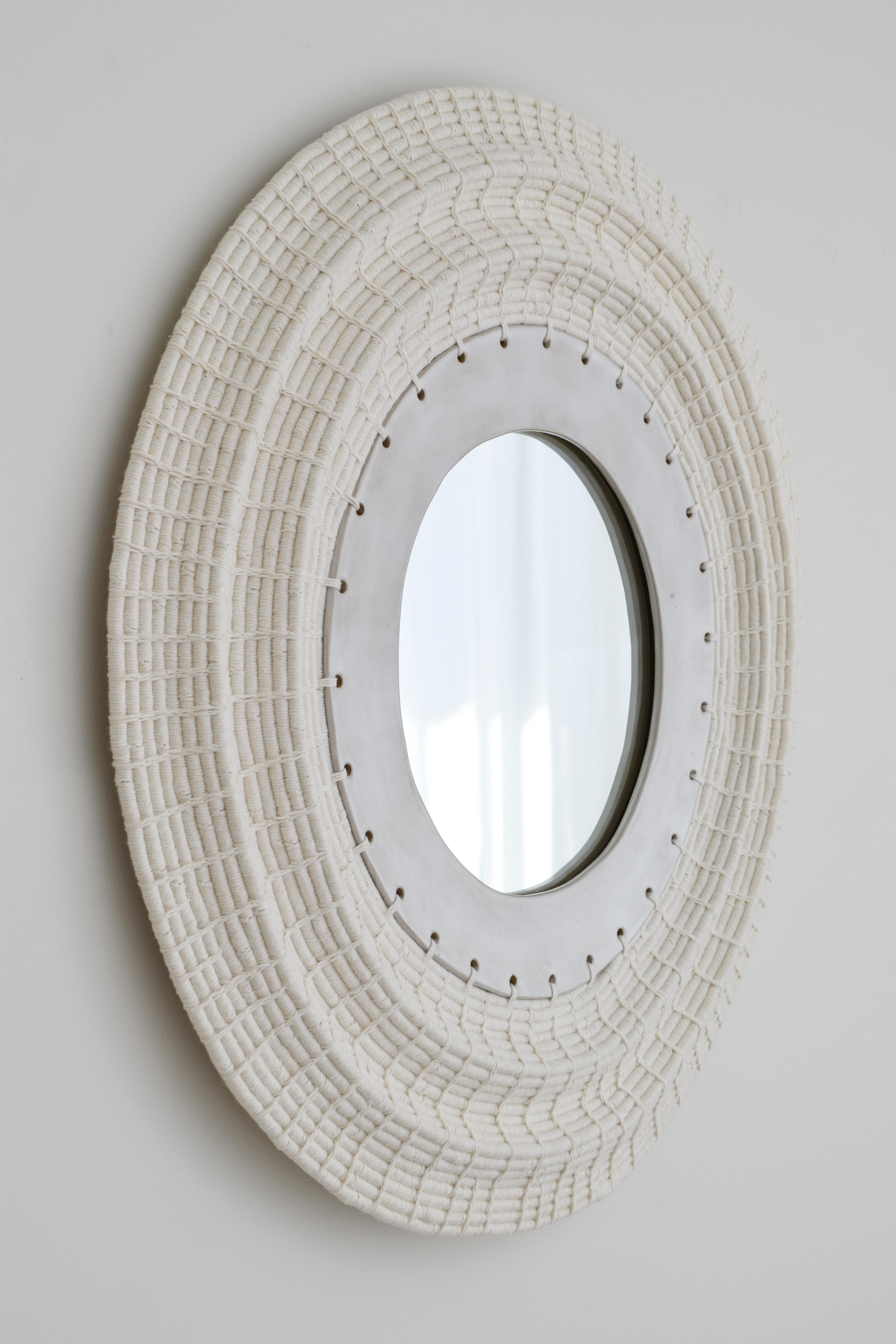 Perfect for hanging in an entryway or in a powder room, this decorative mirror features a woven frame with an undulating, dimensional effect.

Hand formed stoneware frame. Woven cotton exterior frame. Black felt backing, hanging hardware included on
