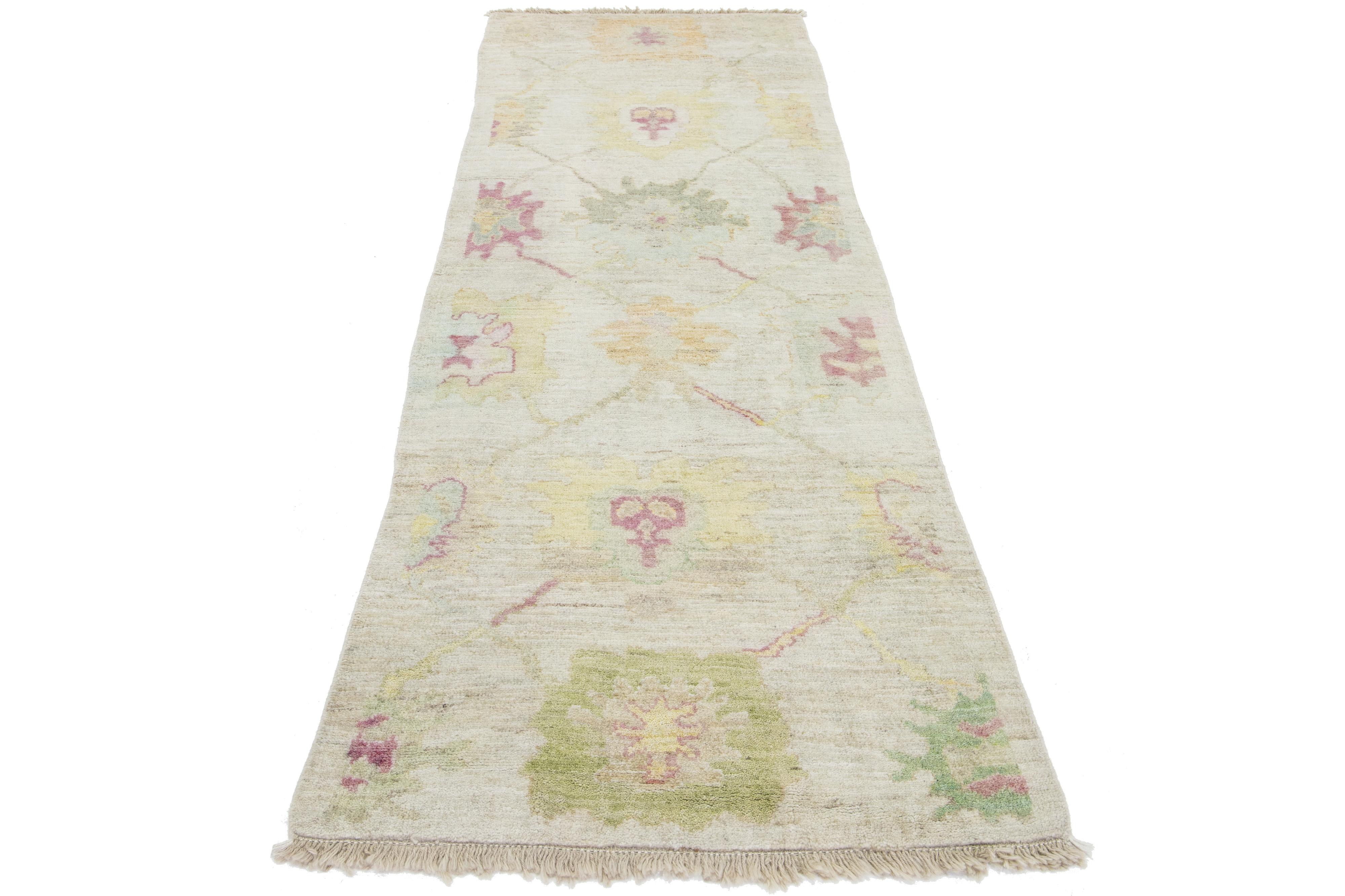 Beautiful modern Oushak hand-knotted wool rug with a beige color field. This Turkish Piece has yellow, blue, green, and red accent colors in a gorgeous all-over floral design.

This rug measures 3' x 9'1