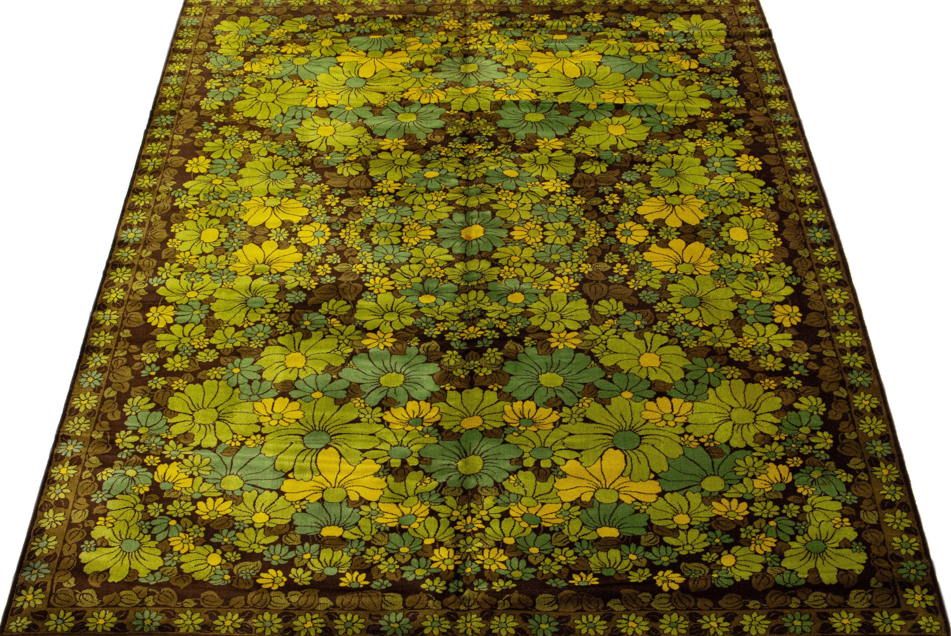 This exquisite wool rug showcases the timeless beauty of the Art & Crafts style, boasting a rich brownfield and a delicate floral pattern with yellow and green accents framed by a subtle olive border. The piece is hand-knotted with utmost precision