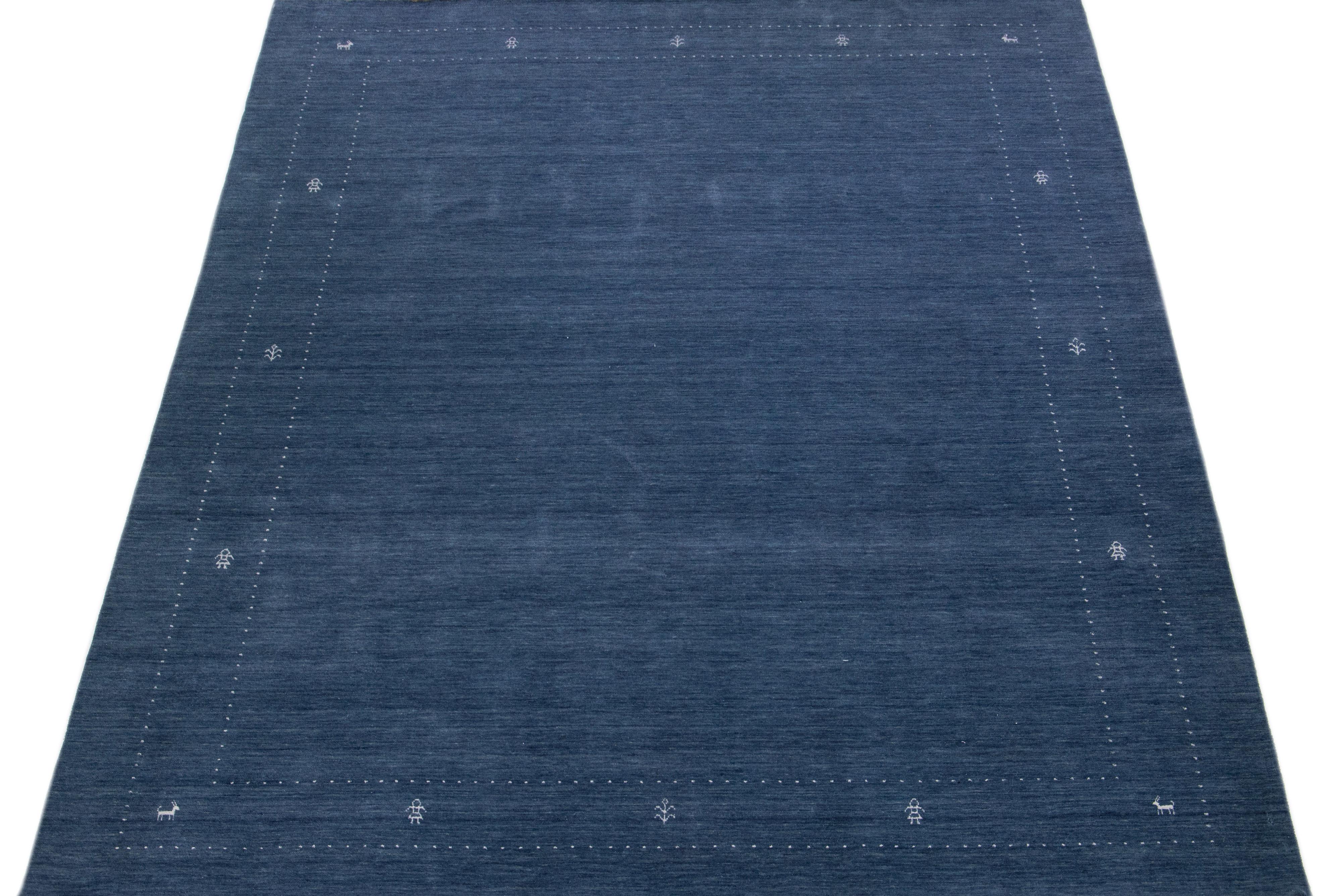 A stunning modern Gabbeh-style hand-woven wool rug boasting a blue color field and exquisite white minimalist design. 

This rug measures: 9'1