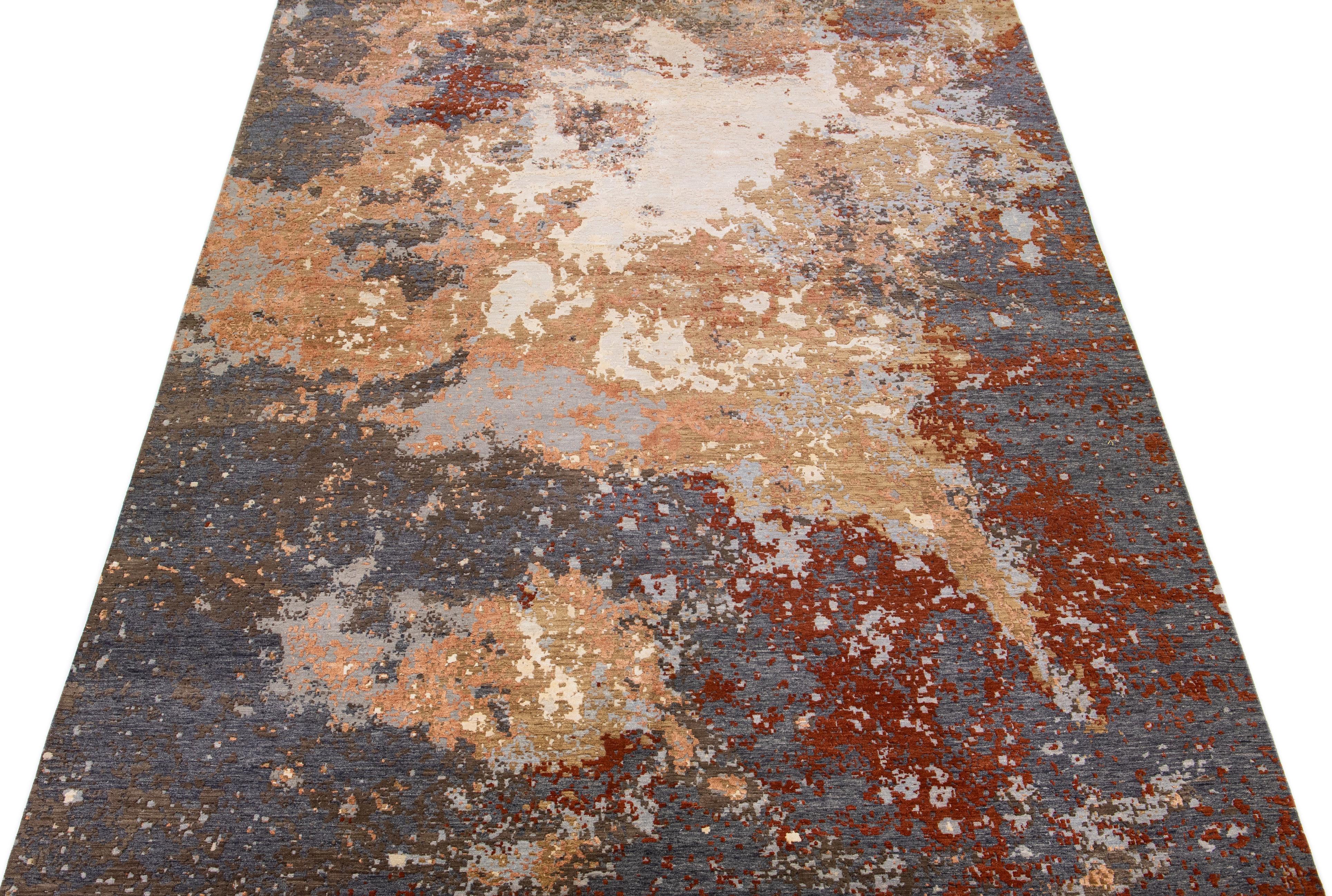 This exquisite hand knotted wool rug features a modern Ikat style with a gray and orange color field, complemented by peach, red, and beige accents in a stunning all-over abstract design.

This rug measures: 10' x 14'.

 