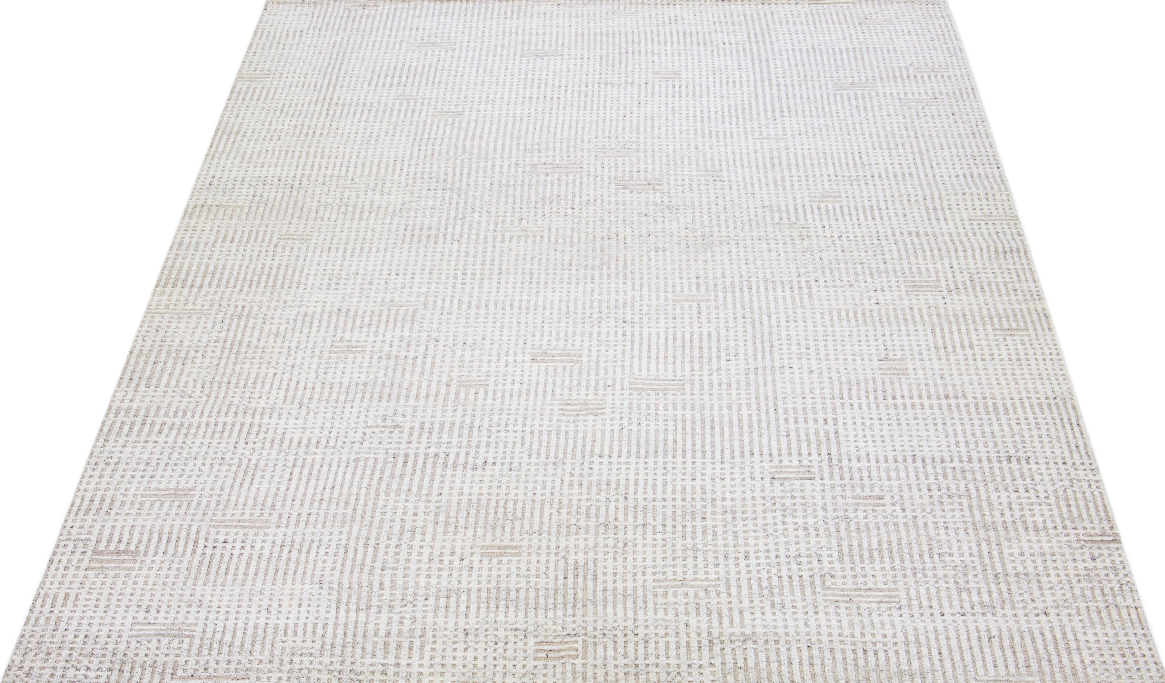 Magnifique tapis moderne en laine nouée à la main de style marocain avec un champ de couleur beige. Ce tapis fait partie de la collection Safi d'Apadana et présente un design minimaliste en blanc et gris.

Ce tapis mesure : 10'2