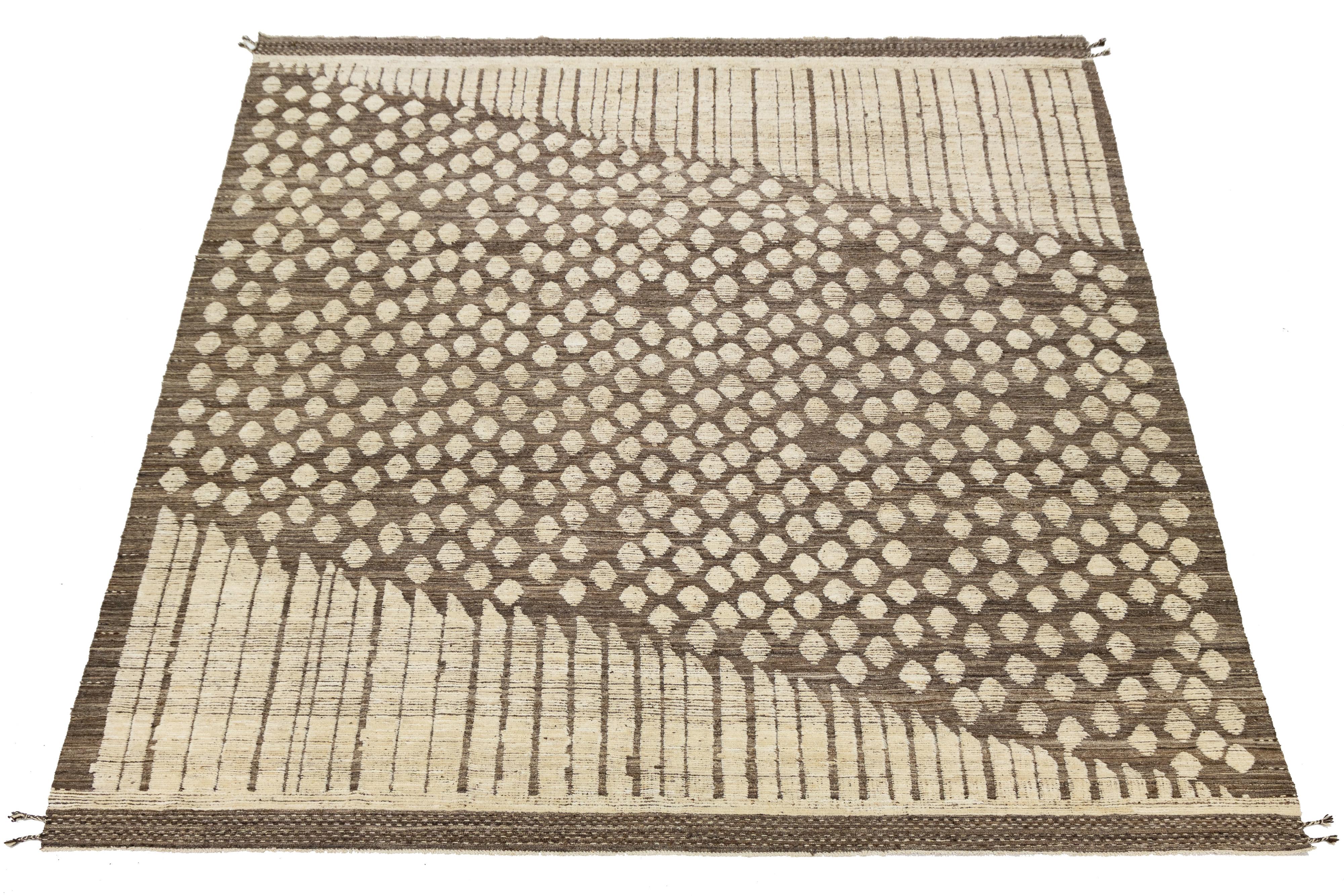 Tessuto a mano in morbida lana, questo tappeto moderno in stile marocchino è caratterizzato da audaci contrasti geometrici nei caldi colori neutri e nel bianco netto. Il suo motivo minimalista e il layout di ispirazione tribale offrono una nuova