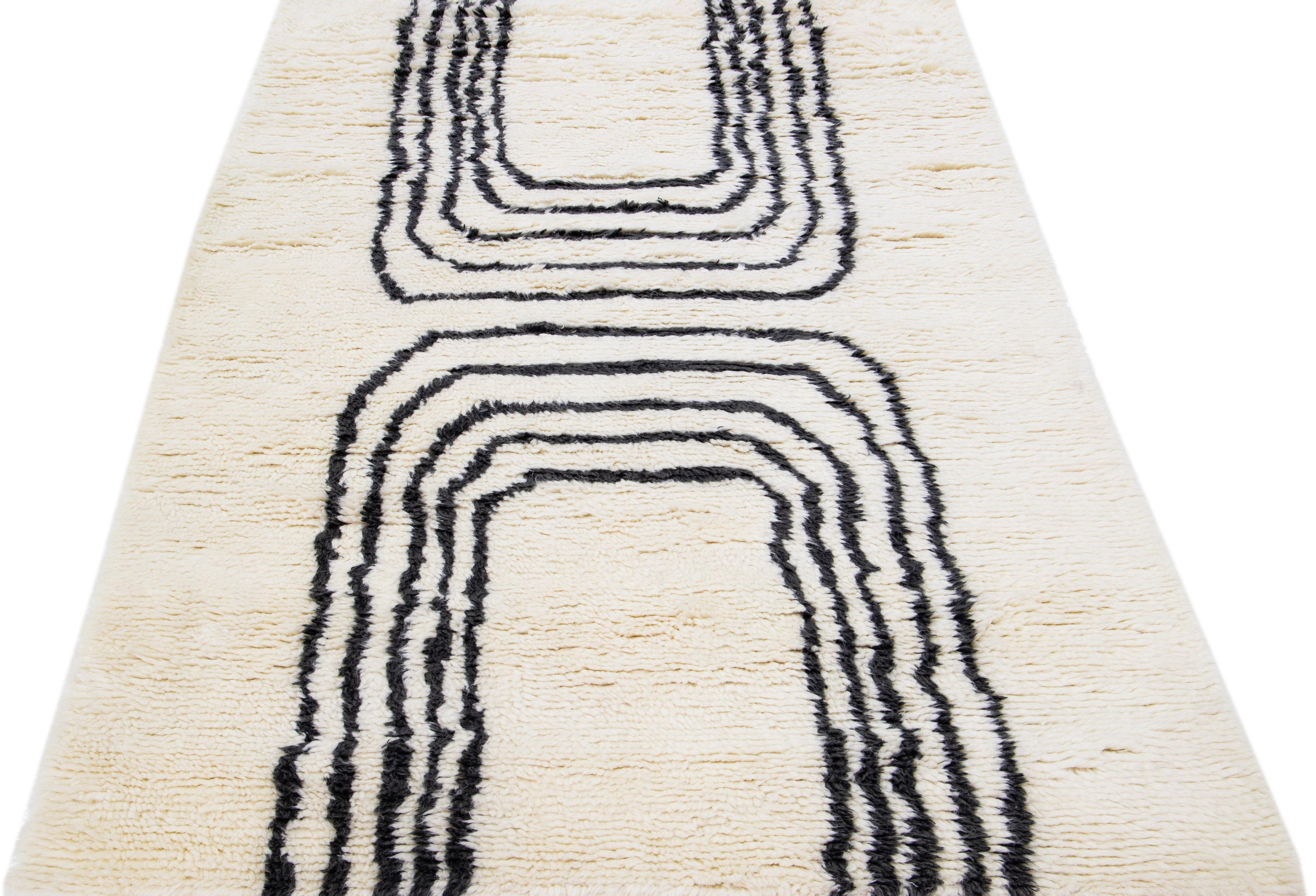 Magnifique tapis moderne de style marocain en laine nouée à la main avec un champ ivoire. Ce tapis fait partie de la collection Safi d'Apadana et présente un design minimaliste dans un coloris gris anthracite.

Ce tapis mesure : 5' x 8'.

Nos tapis