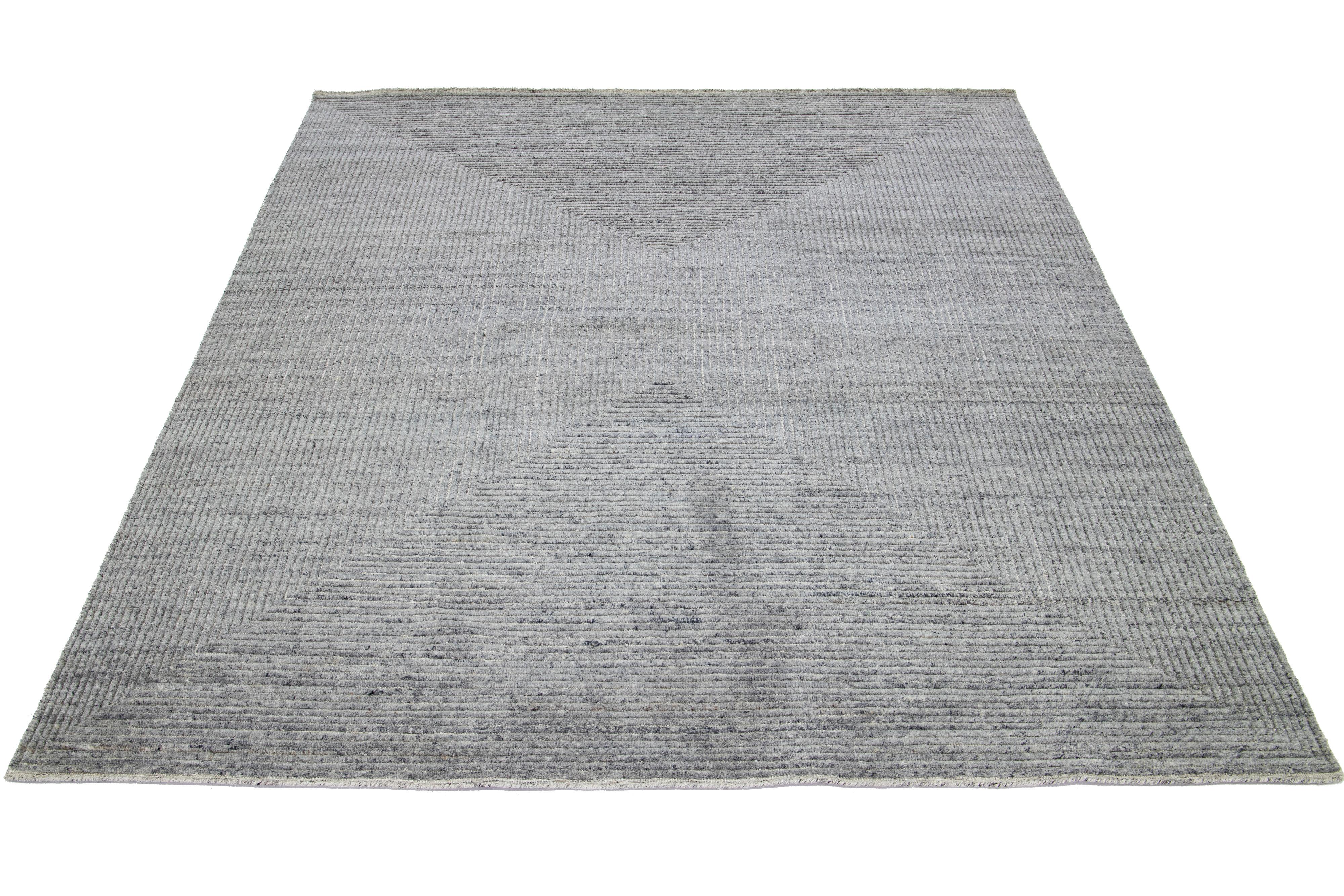This hand-knotted Moroccan wool rug exhibits an Organic Modern style, featuring a geometric design in hues of light gray.

This rug measures 7'11