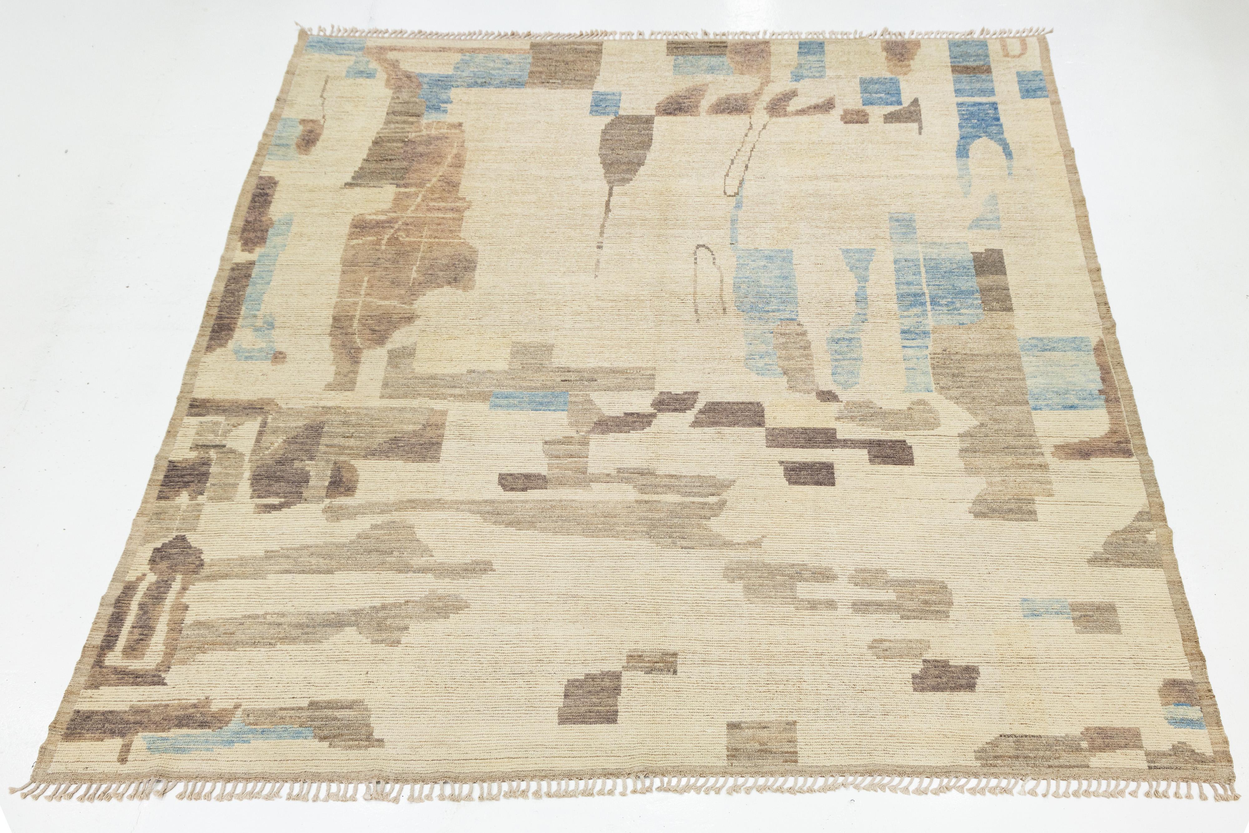 Ce tapis en laine de style marocain tissé à la main présente un design abstrait audacieux dans des teintes naturelles de beige, de marron et de bleu. Ses formes organiques et sa palette terreuse évoquent les paysages désertiques et le patrimoine