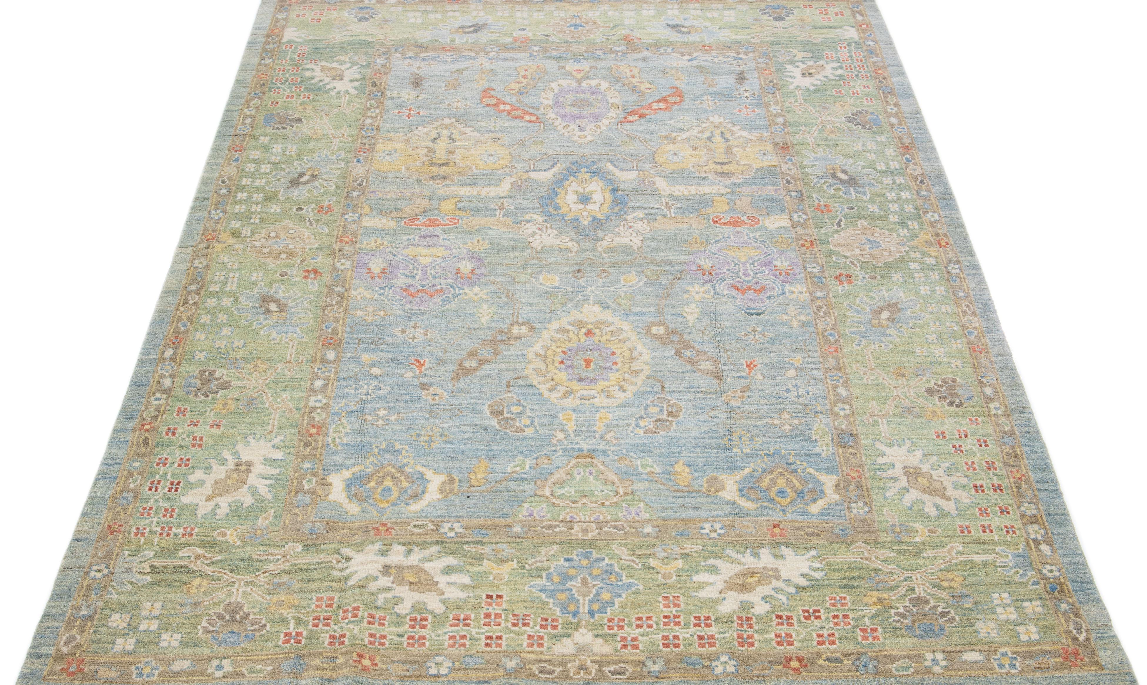 Bellissimo tappeto moderno in lana annodata a mano in stile Oushak con campo blu. Questo pezzo ha una cornice verde con accenti di colori vivaci in uno splendido disegno floreale all-over.

Questo tappeto misura: 6'9