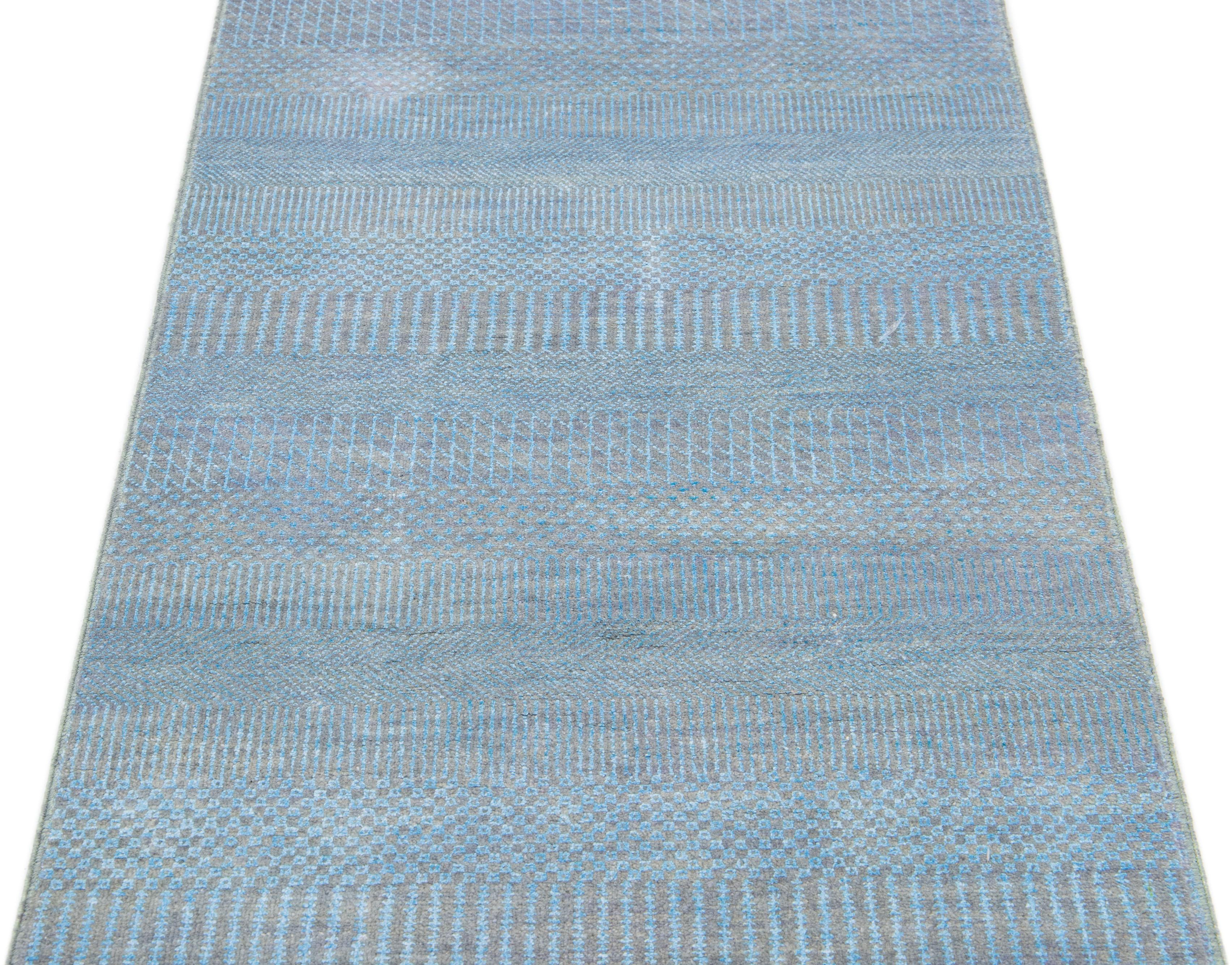 This long hand-knotted rug is made of wool. It features a subtle light blue color scheme accented by an all-over geometric pattern—an ideal addition to any contemporary interior.

This rug measures 2'7