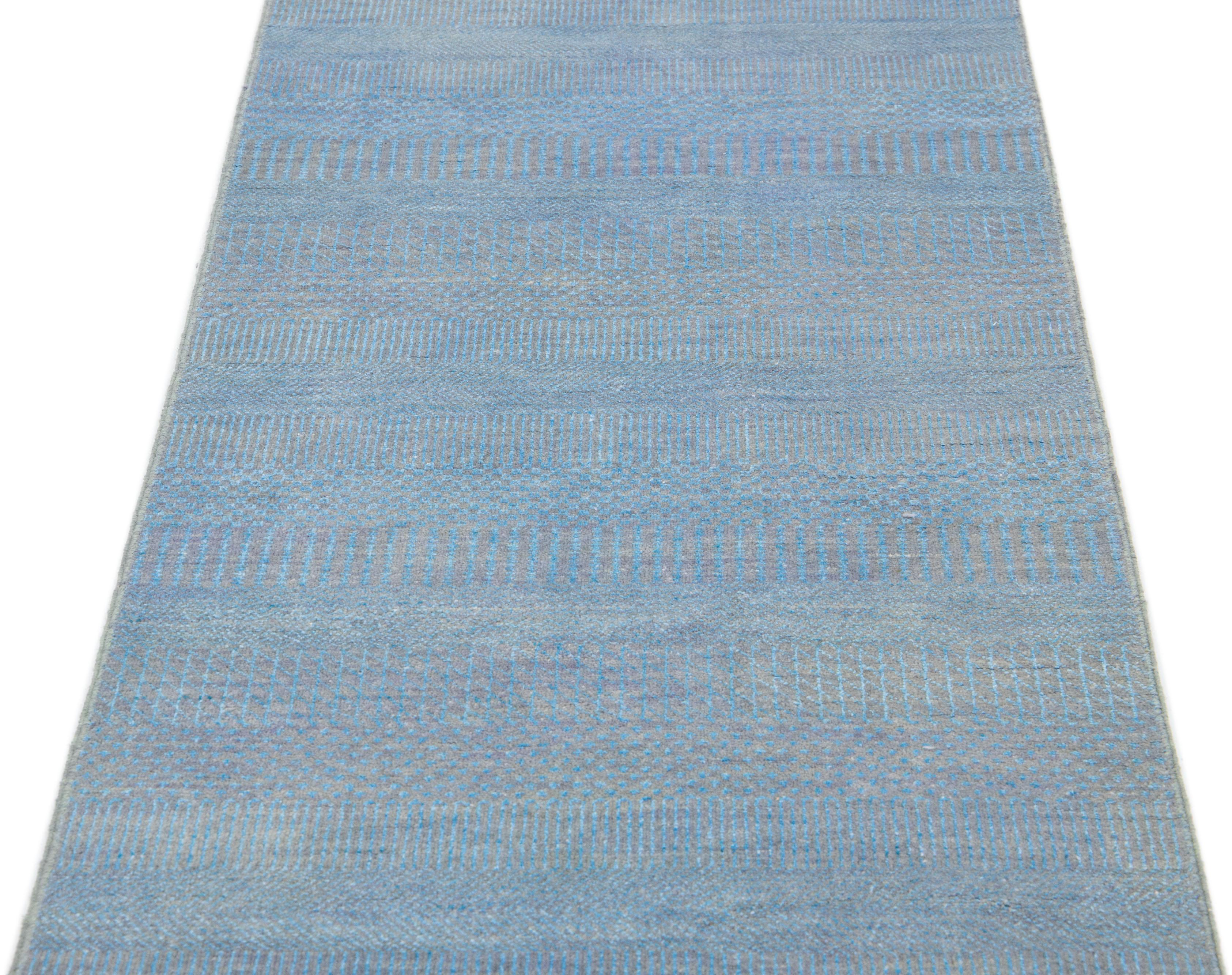 This long hand-knotted rug is made of wool. It features a subtle light blue color scheme accented by an all-over geometric pattern—an ideal addition to any contemporary interior.

This rug measures 2'7
