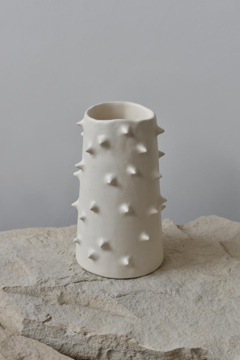 Magnifique vase en céramique blanche, parfait pour mettre en valeur vos compositions florales préférées. Offrant une perspective unique sous tous les angles, ce vase en poterie fait à la main estompe gracieusement la frontière entre fonctionnalité