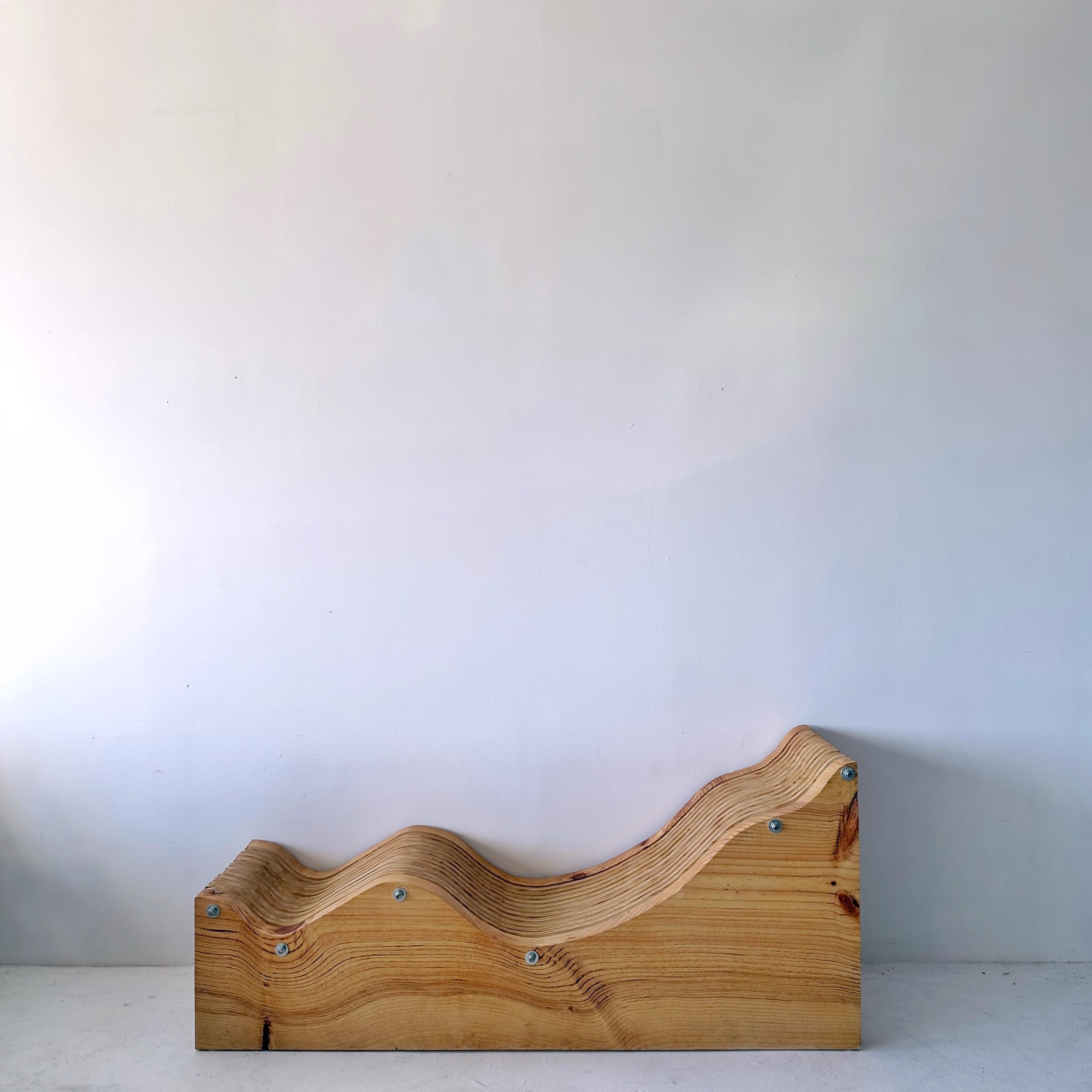 Chaise longue ergonomique et ondulée fabriquée à la main. Des feuilles de contreplaqué découpé sont maintenues entre de solides dalles de pin de Monterrey, dont le grain ondulé reflète le rythme des couches de contreplaqué.

📍 Consultable à Los