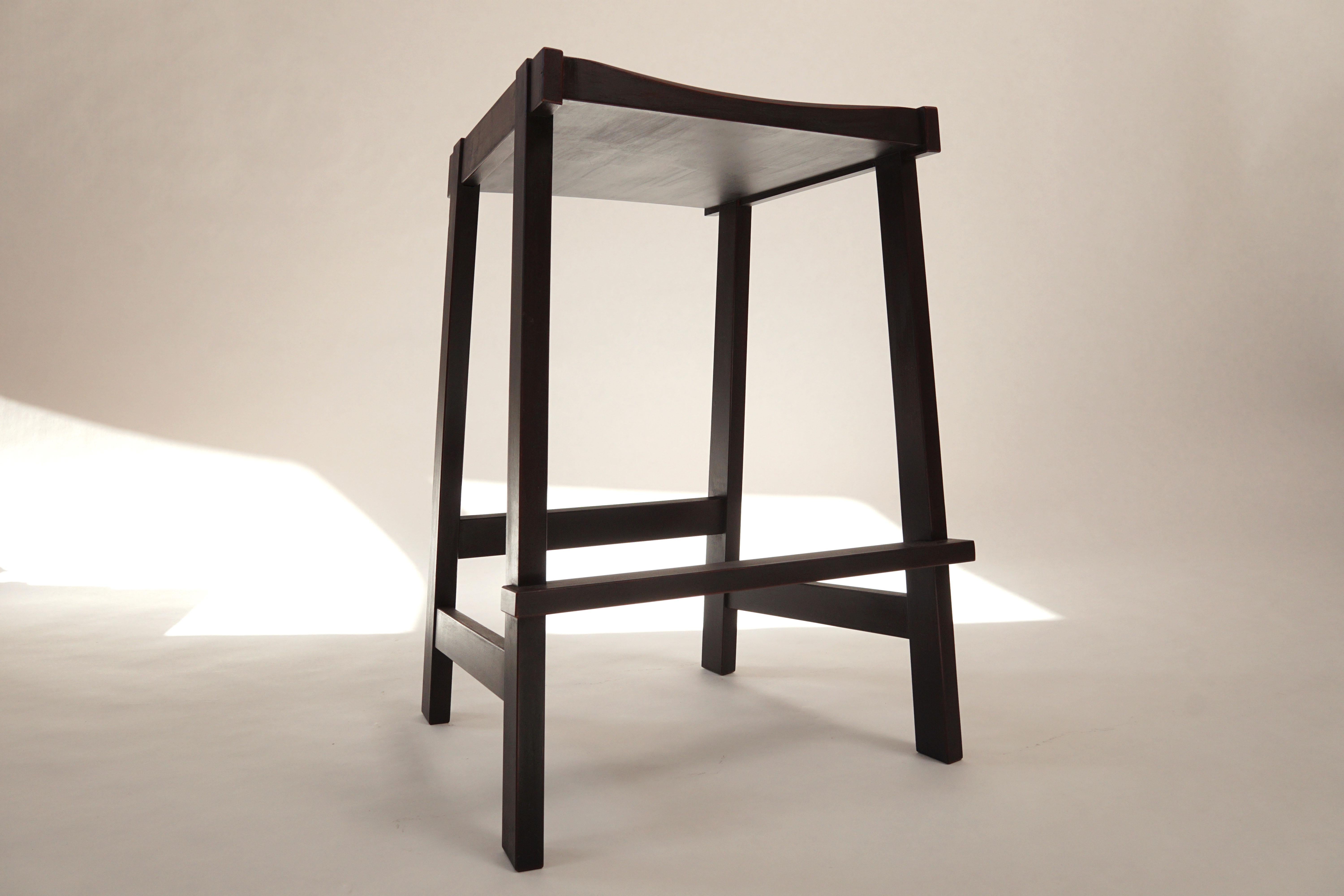 The Montrose Stool, a sharp, bold, angular form. Made from solid hardwoods with a carved seat for comfort. Constructed with lots of exposed joinery and interesting details. The top of the legs are bridle joints, let into the seat. The foot rest is