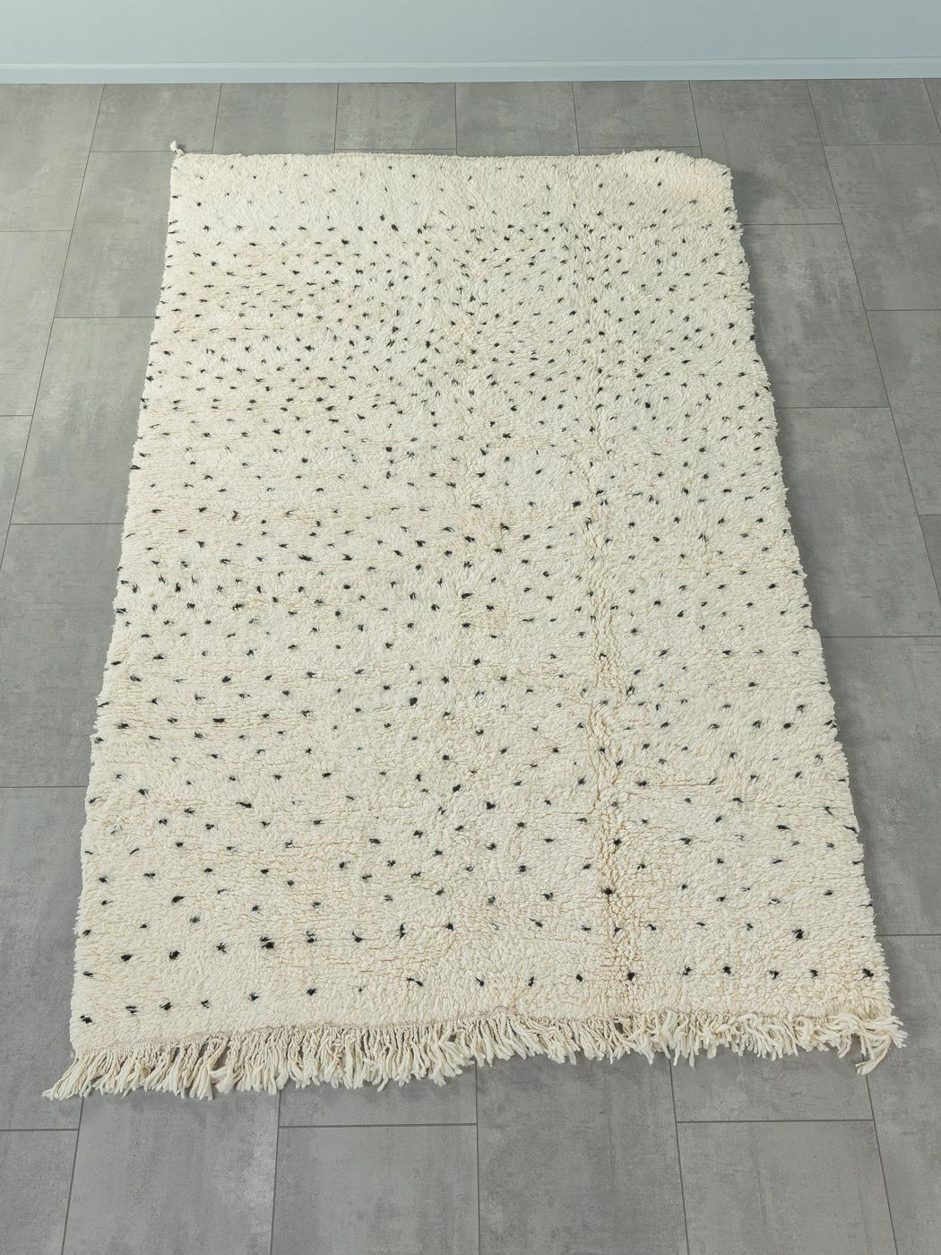 Tiny Dalmatian ist ein moderner Teppich aus 100 % Wolle - dick und weich, angenehm zu tragen. Unsere Berberteppiche werden von Amazigh-Frauen im Atlasgebirge handgewebt und handgeknüpft. Diese Gemeinschaften stellen schon seit Tausenden von Jahren