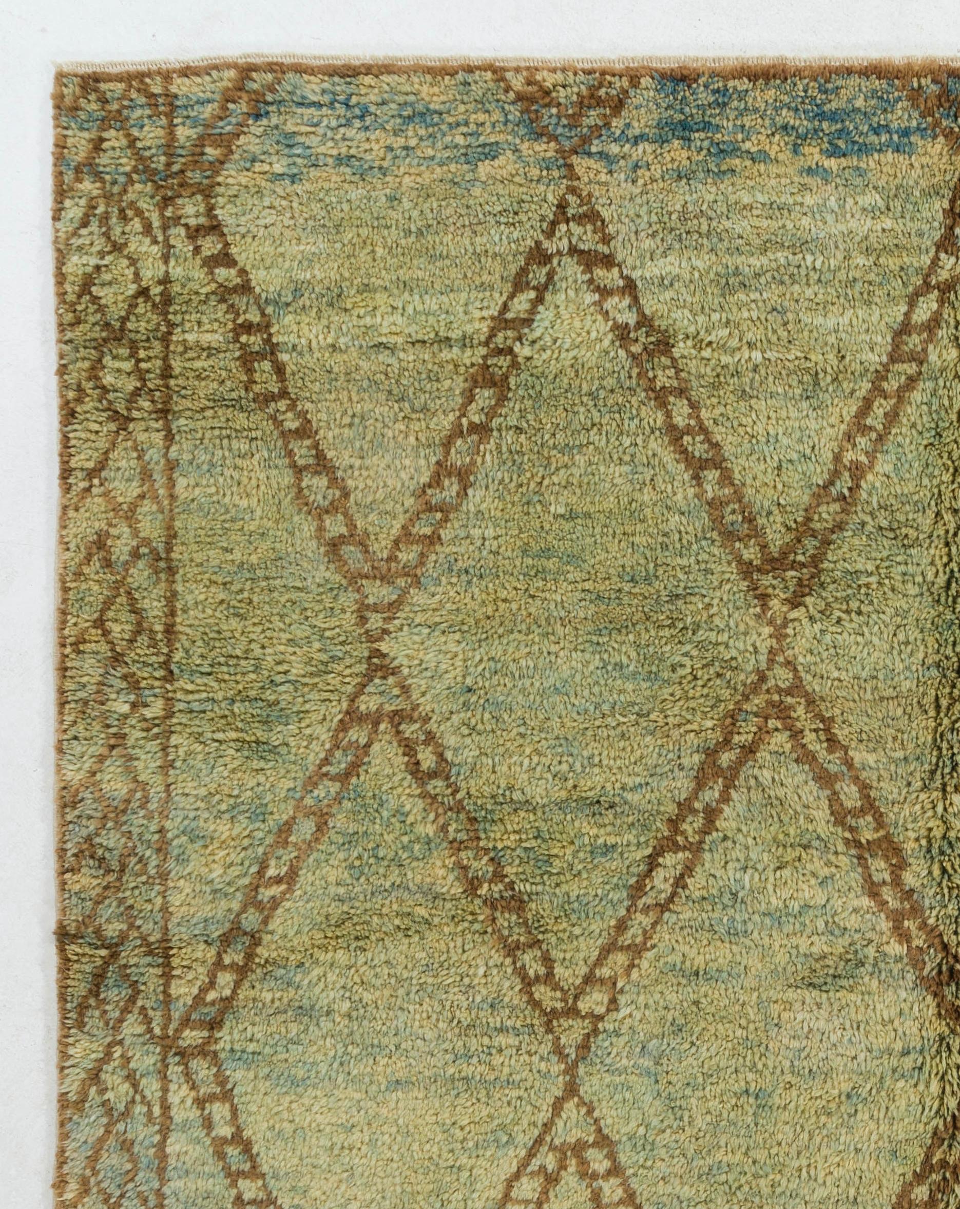 A Moroccan Berber design contemporary hand-knotted rug made of organic wool in a sophisticated, warm and earthy color palette of olive green, brown and light blue. It features an all-over design of lozenge-shaped, wide-edged lattices and two lateral
