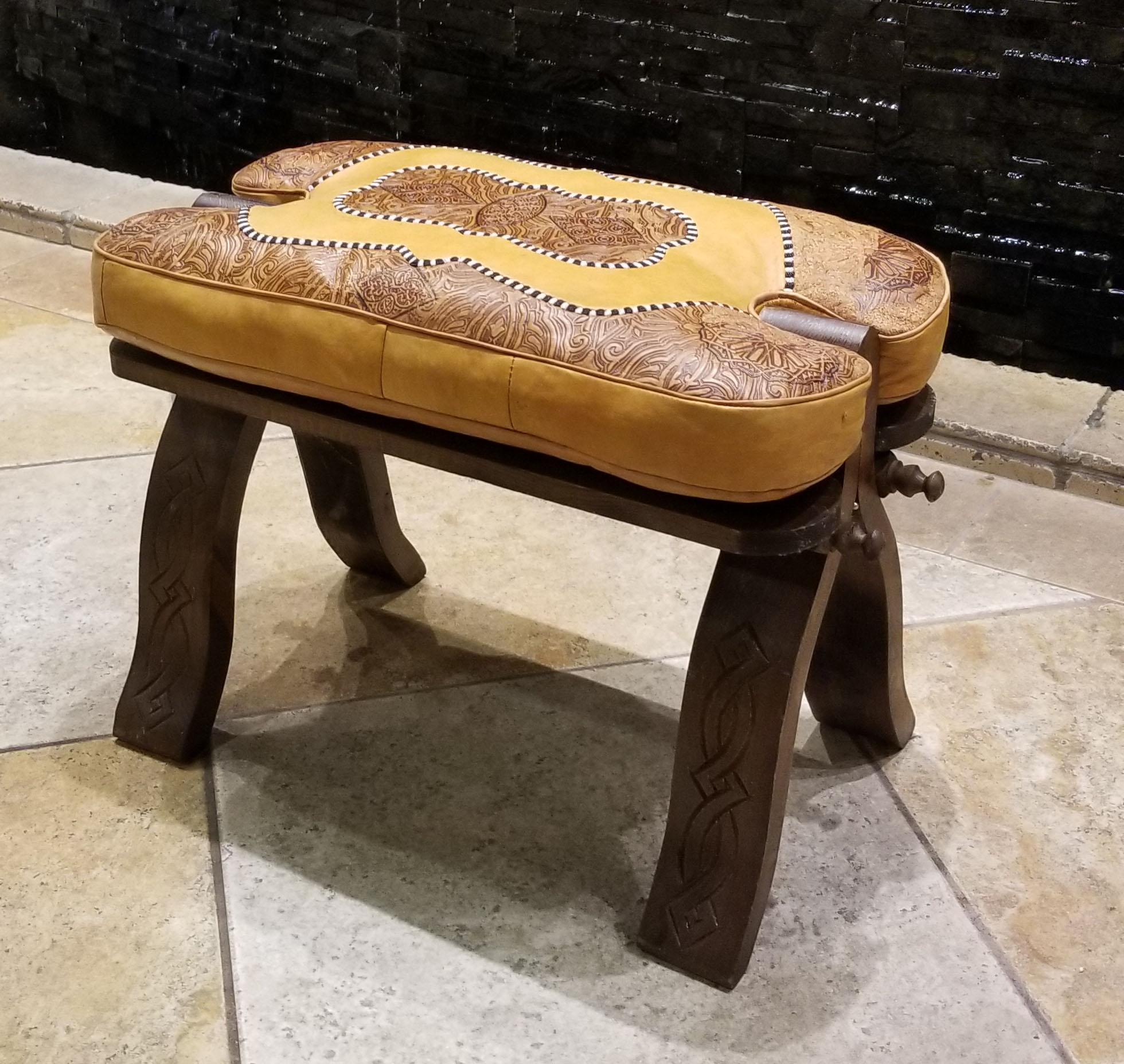 This is a great alternative to poufs and ottomans.
Handmade Moroccan camel saddle with genuine leather cushion and carved cedar wood base, measuring approximately 25 inches long, 13