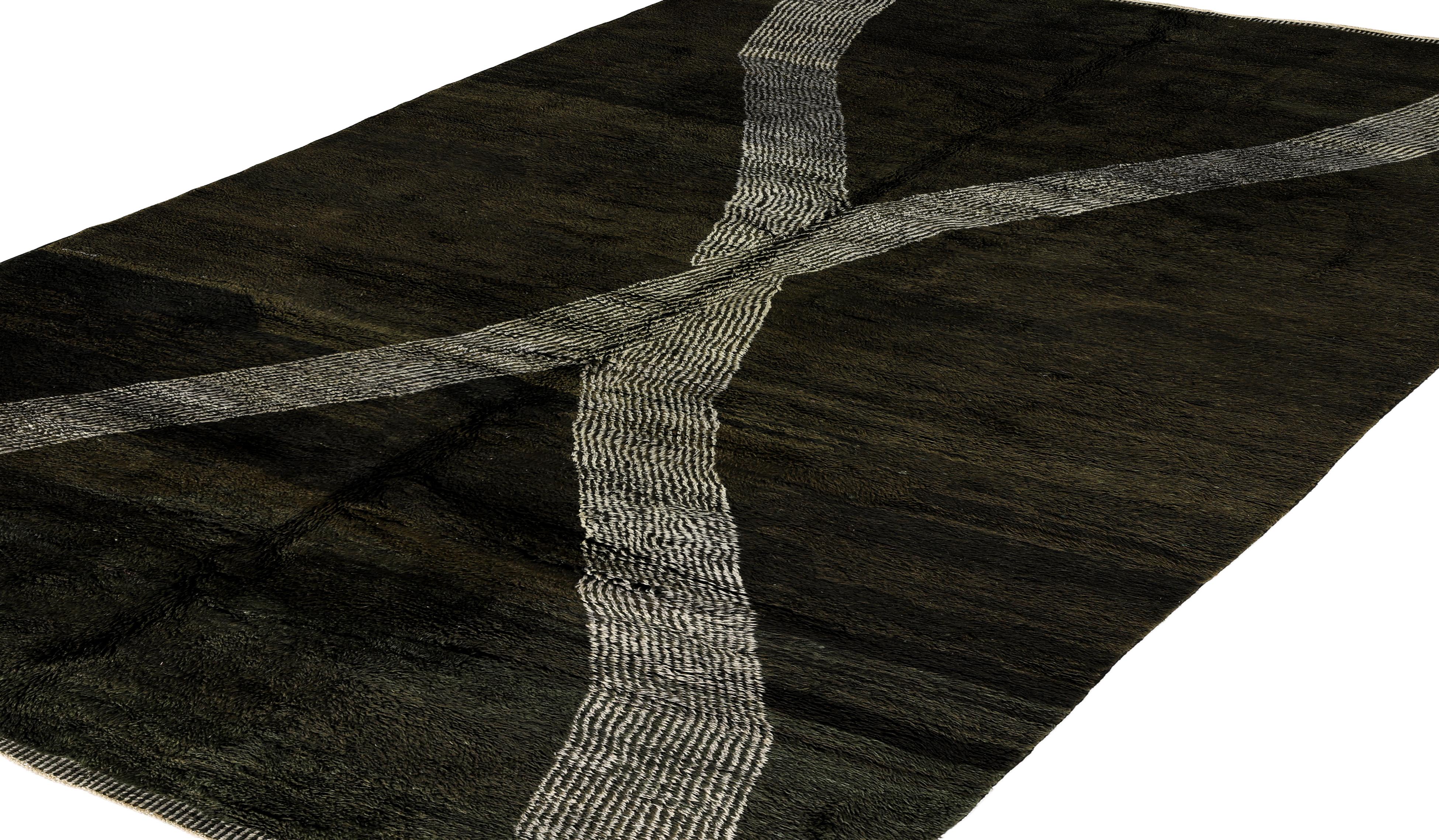 This striking handmade Moroccan rug features a bold ivory crisscross pattern over a deep charcoal wool ground, creating a minimalist yet impactful design. The expressive X-shaped motif is woven using handspun wool and natural dyes, lending it