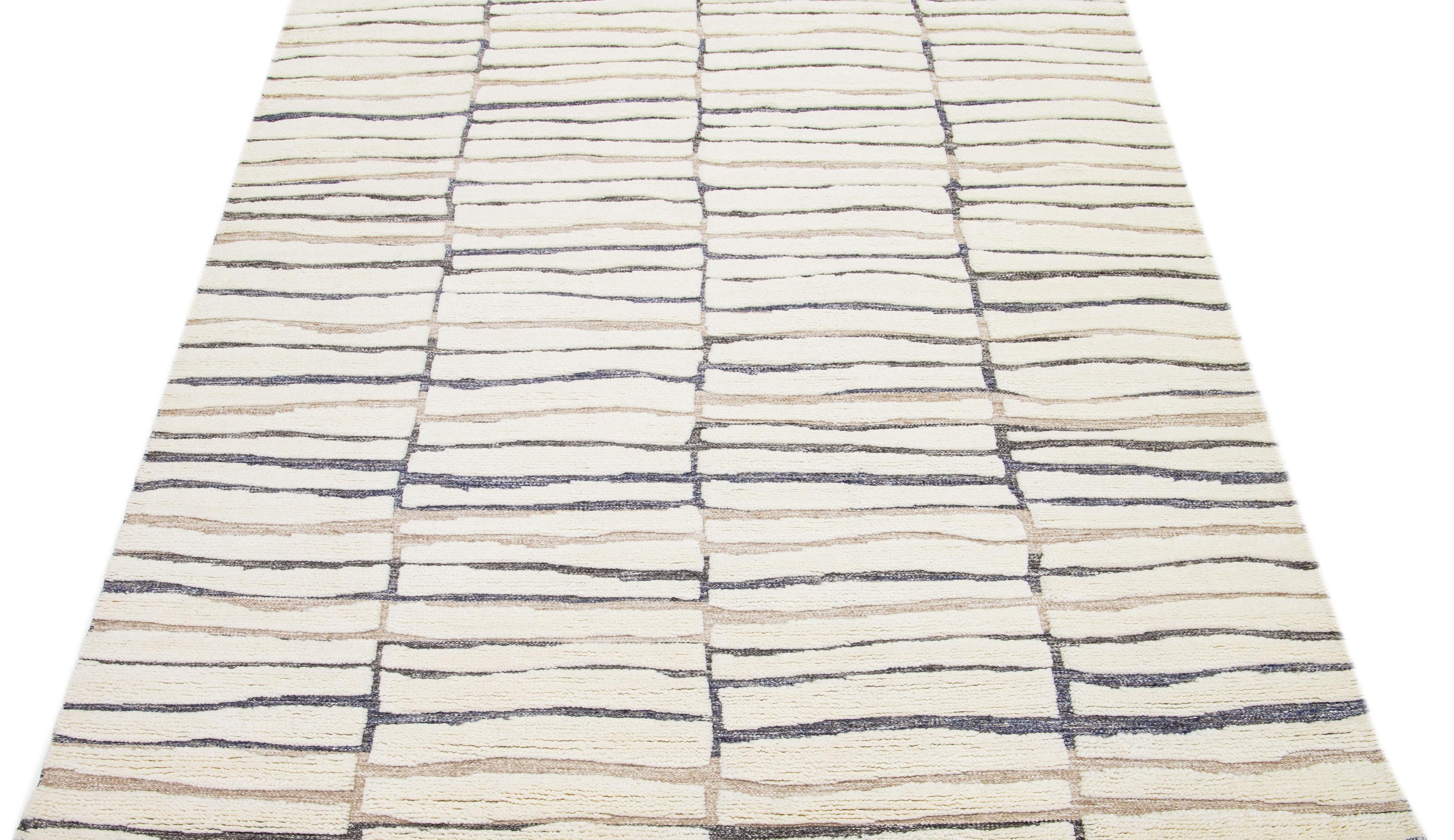 Featuring a contemporary Moroccan design, this meticulously crafted wool rug effortlessly highlights a serene Ivory shade. Complemented by a captivating brown and gray backdrop, these harmoniously blended colors form a flawless abstract composition
