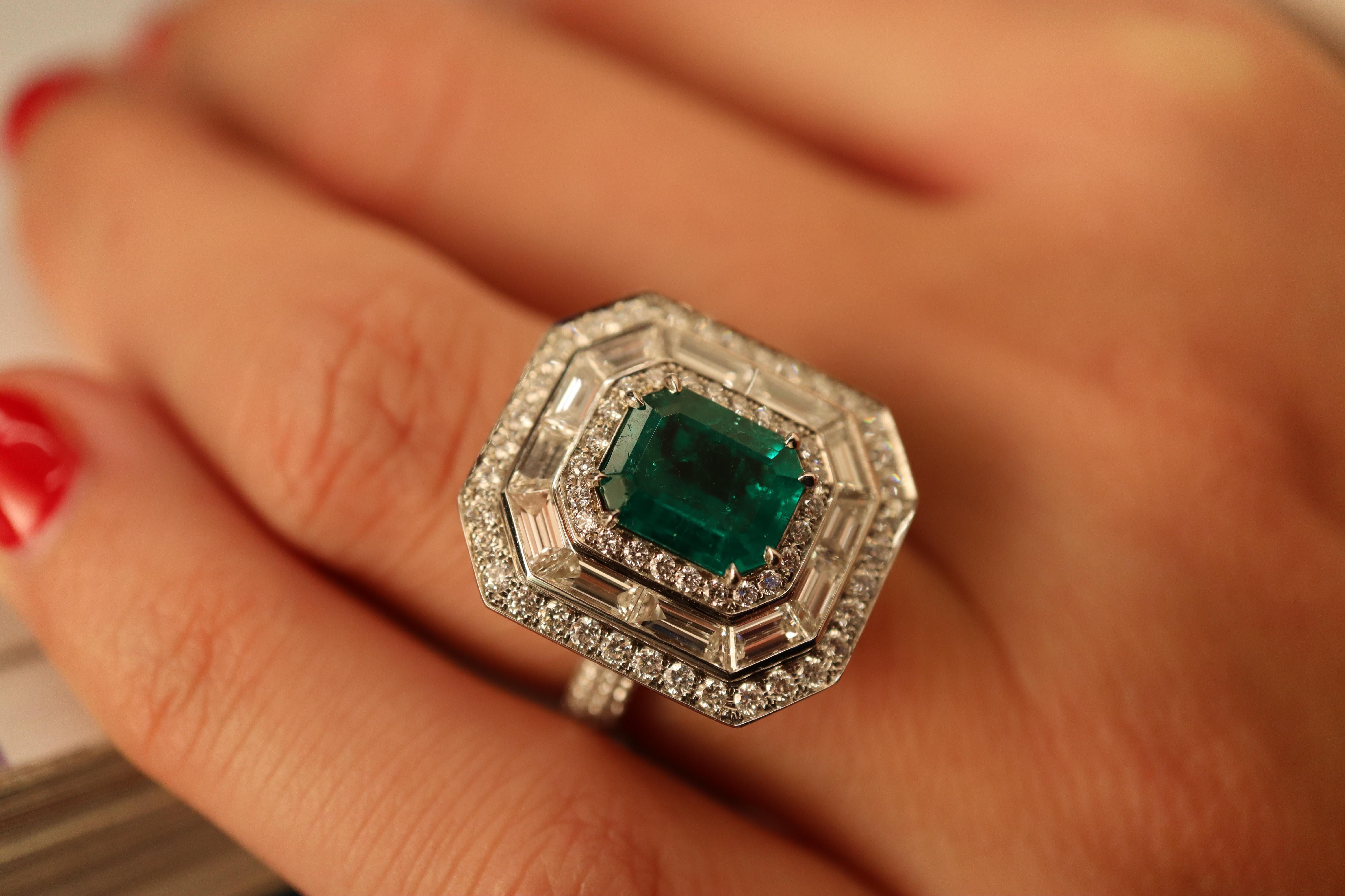 A brilliant and deeply saturated bright-green emerald is dynamically presented in a hand fabricated Art Deco-inspired platinum setting. The magnificent gemstone (even our expert photography doesn't begin to capture the true depth of color), which is